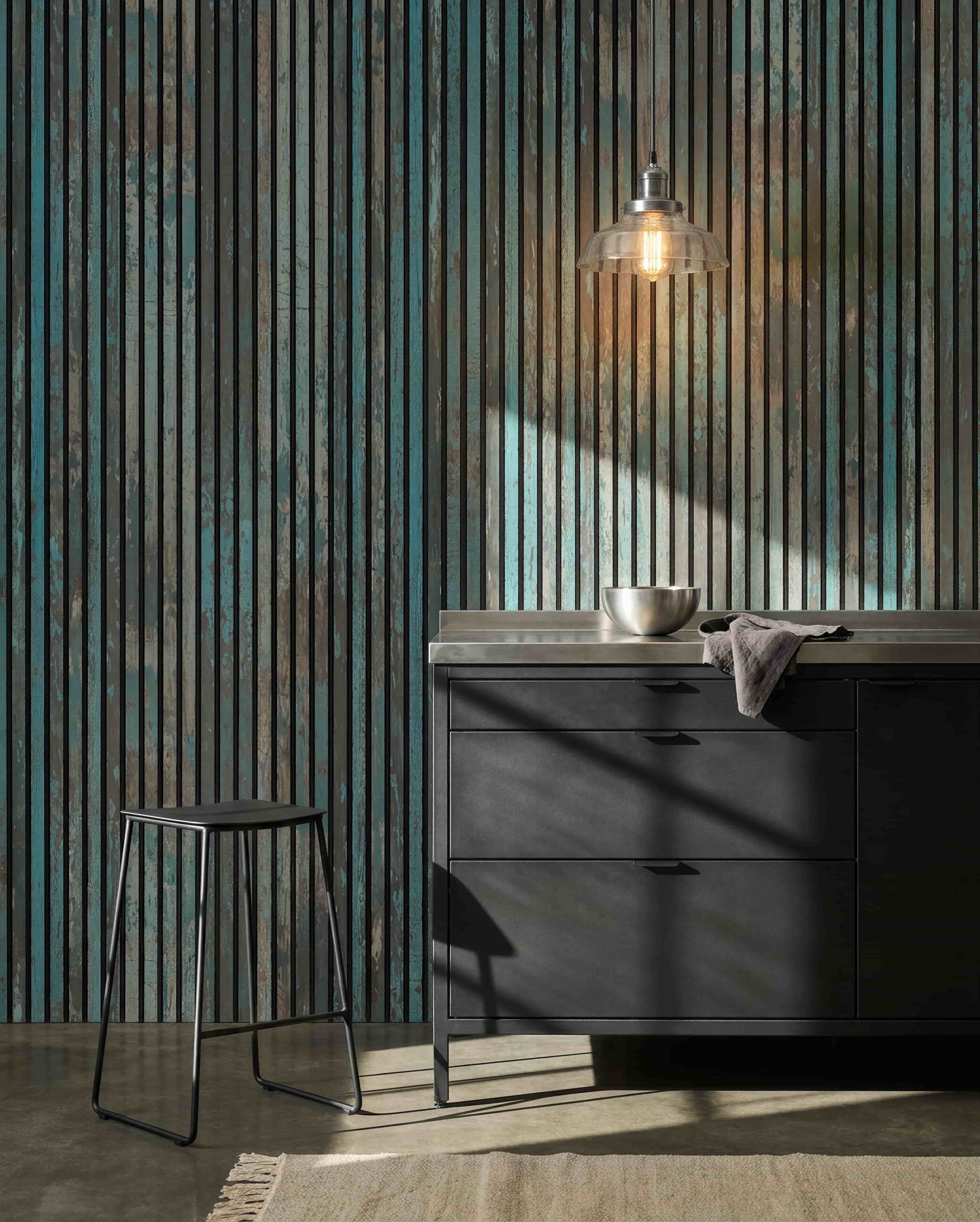 Cocina moderna con taburetes black, armarios black, un cuenco bajo una lámpara de bombilla y un Panel acústico WoodUpp Akupanel Oxide Blue en la pared para mejorar el confort acústico.