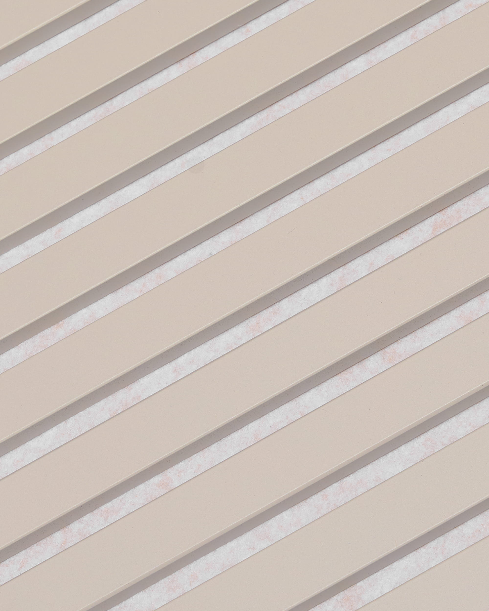 Las lamas diagonales de color beige con espacios blancos forman un diseño a rayas en el panel acústico WoodUpp Akupanel, con acabado de fieltro «Soft Linen Light Beige», de 240 x 60 cm.