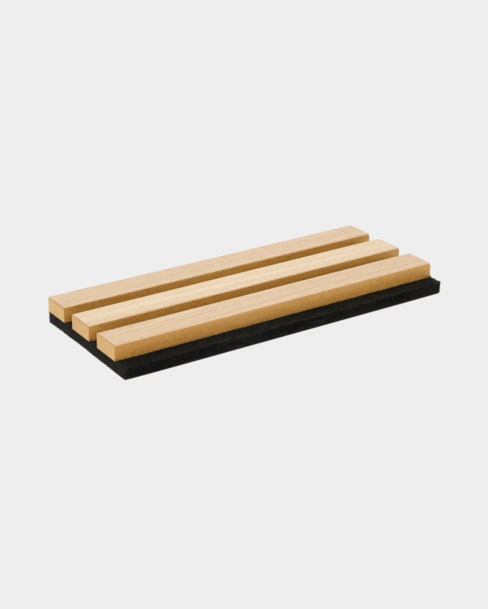 La bandeja de muestras WoodUpp Akupanel en Classic Oak incluye tres lamas acústicas de madera sobre una base de fieltro black, y muestra el diseño nórdico y el contraste entre materiales.