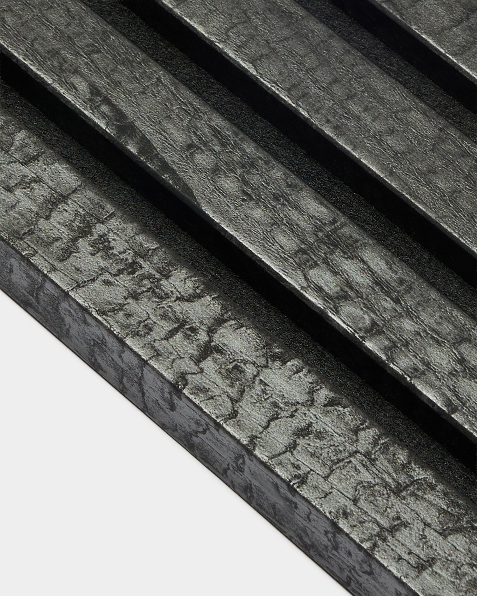 Lámina final WoodUpp Akupanel en carbón (2,2 cm), con paneles acústicos de madera diagonales y texturizados con un acabado carbonizado black para instalación en pared.