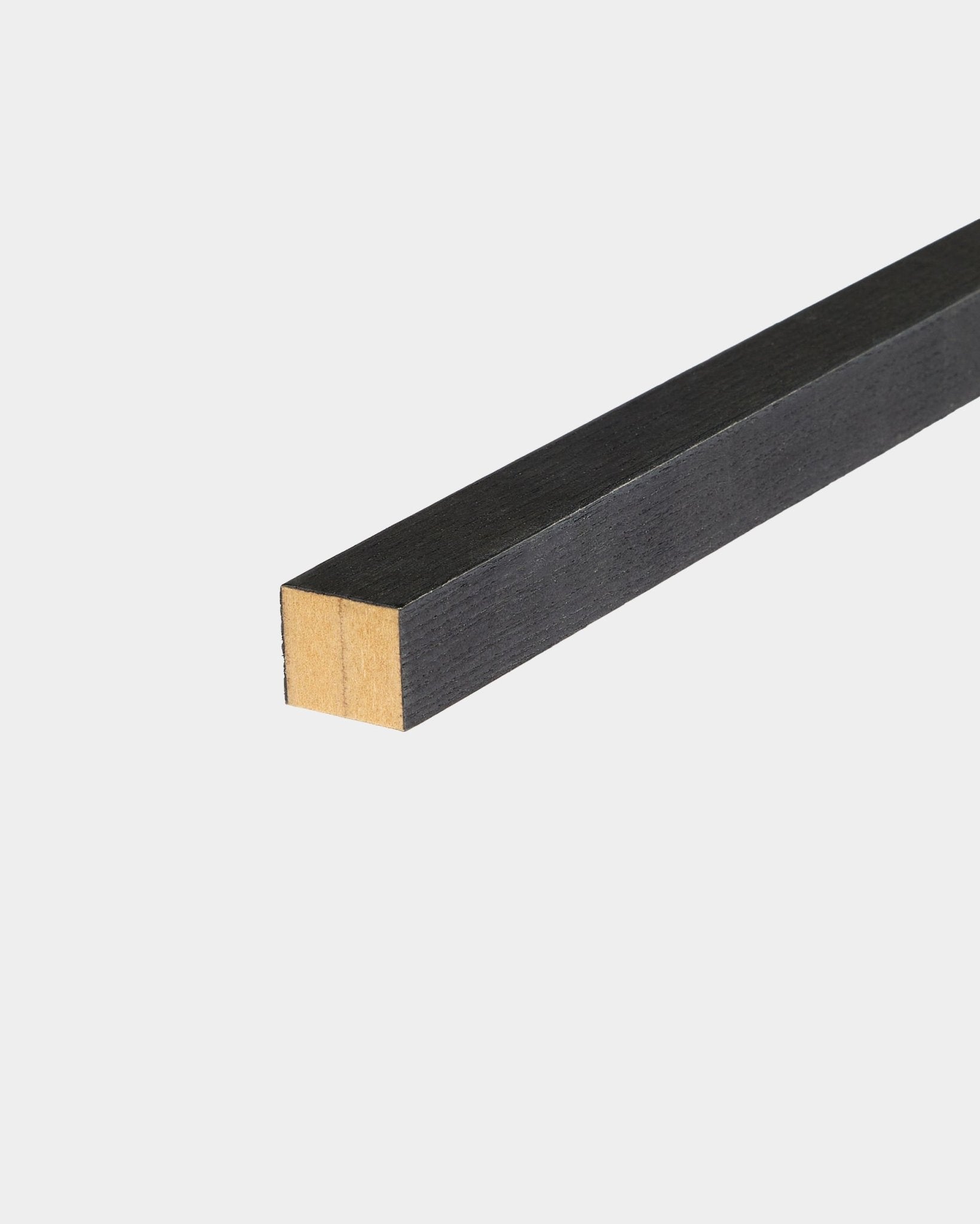 Lámina final WoodUpp Black Ash, 2,2 cm, diseñada para instalación Akupanel Panel acústico, apoyada sobre una superficie blanca con un extremo sin terminar.