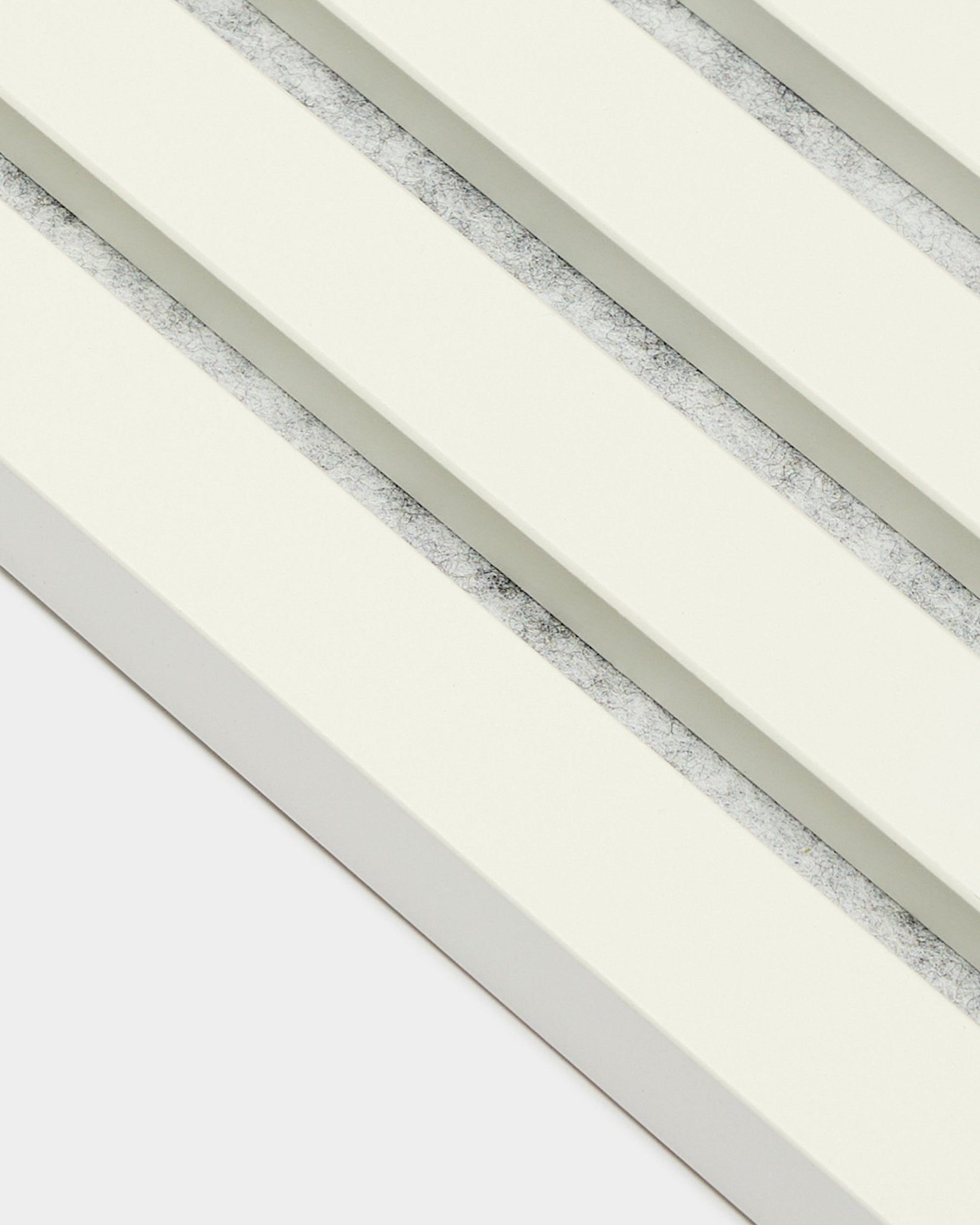 Cuatro paneles acústicos WoodUpp Akupanel End Lamella/Snow (2,2 cm) dispuestos en diagonal, con lamas en blanco roto y separaciones grises texturizadas de estilo nórdico.
