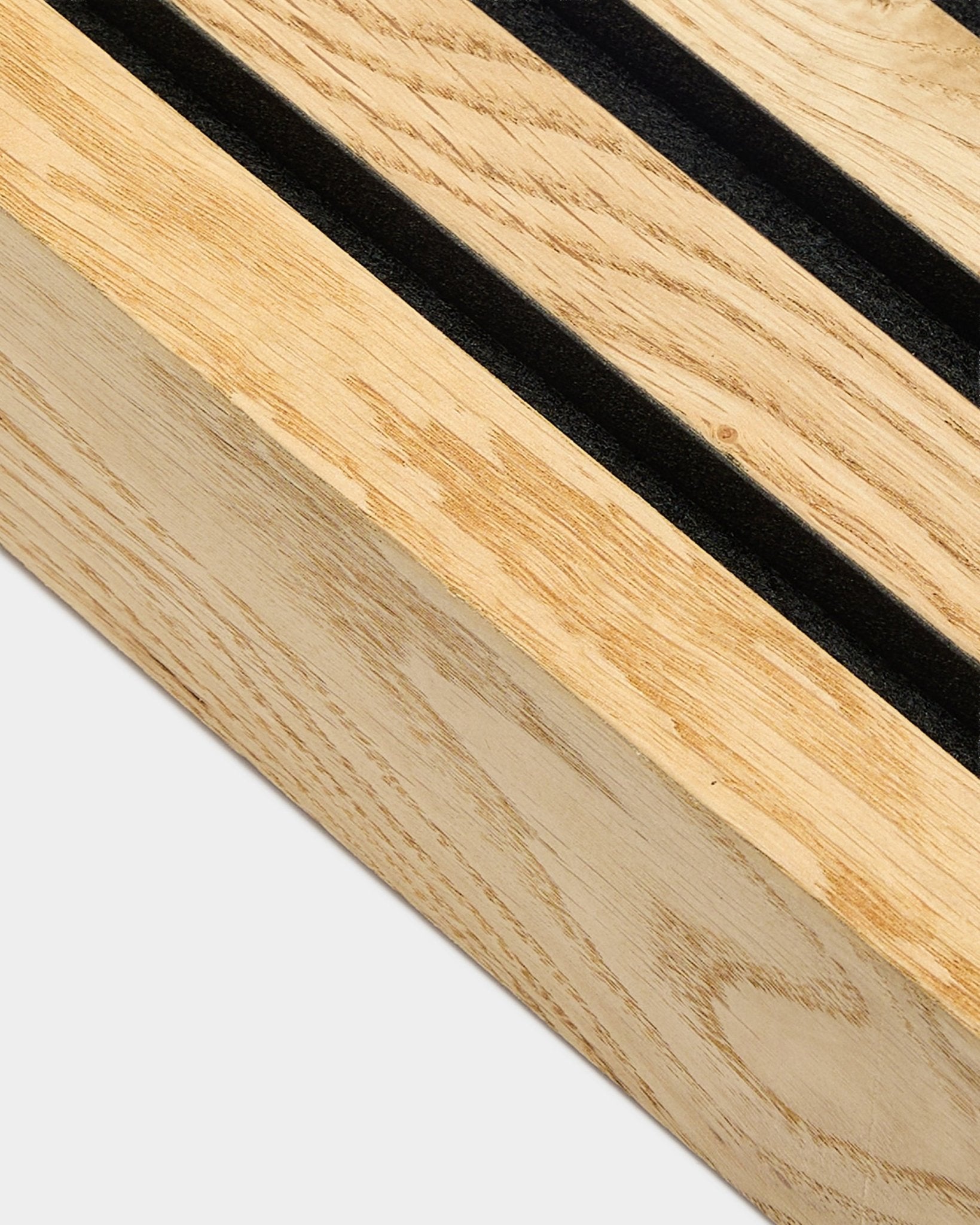 Primer plano de una lámina terminal WoodUpp Akupanel en Rustic Natural Oak, de 6,7 cm, con ranuras paralelas black y un marco de MDF para instalación acústica en pared.