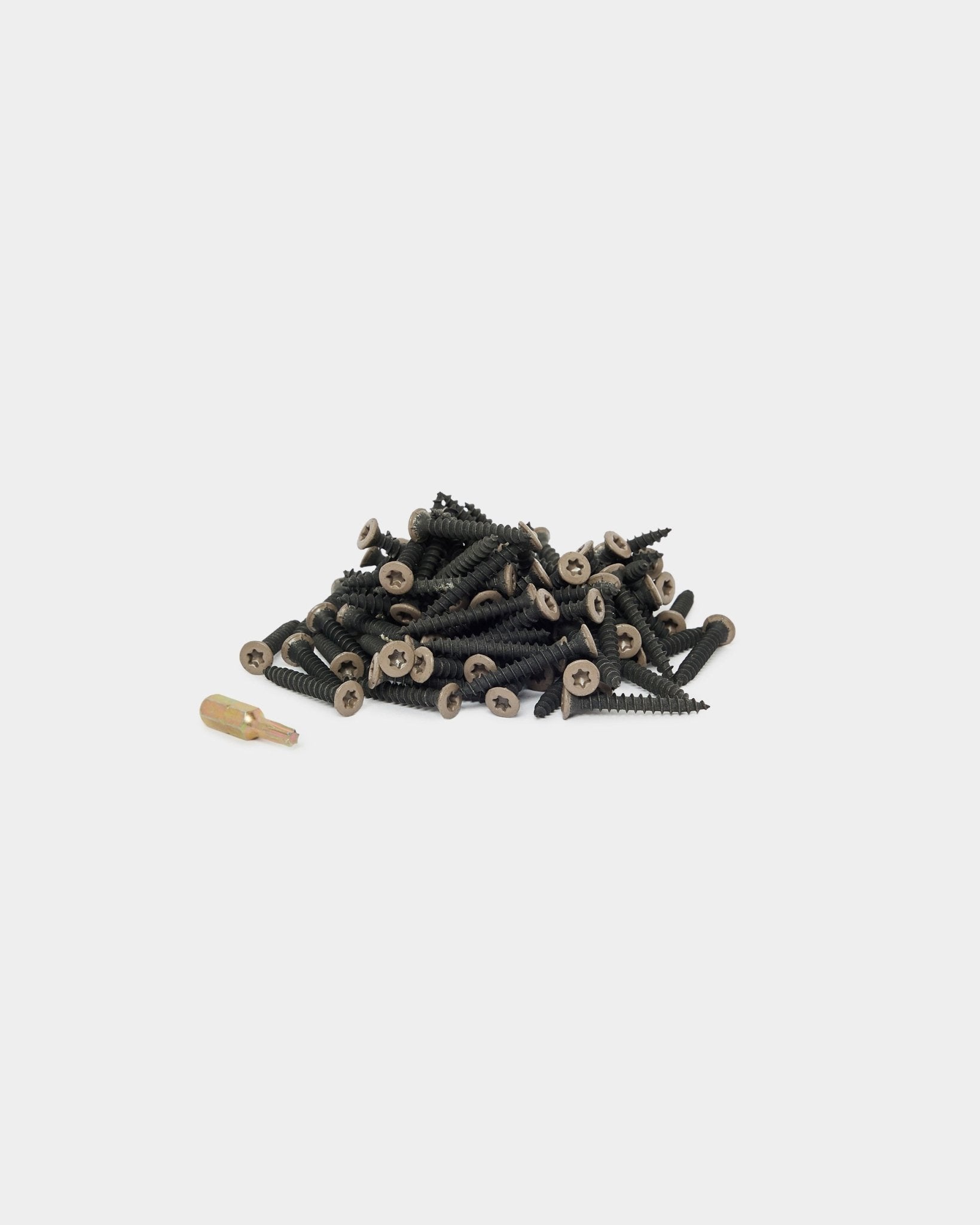 Tornillos de instalación WoodUpp Warm Grey (100 uds.) y una punta de destornillador dorada colocados sobre un fondo blanco, aptos para la instalación de Panel acústico o accesorios para paneles.