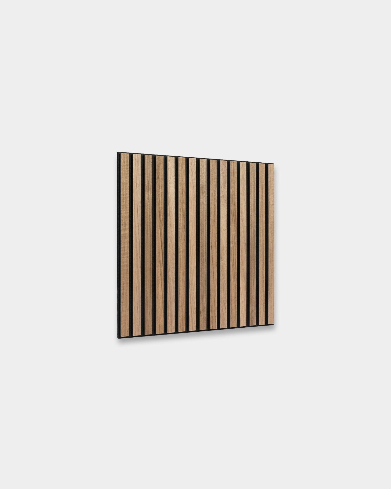 WoodUpp Akupixel Panel acústico en nogal, 60x60 cm, presenta lamas de nogal espaciadas de forma uniforme con huecos de black, montadas sobre una pared gris claro para un diseño escandinavo.