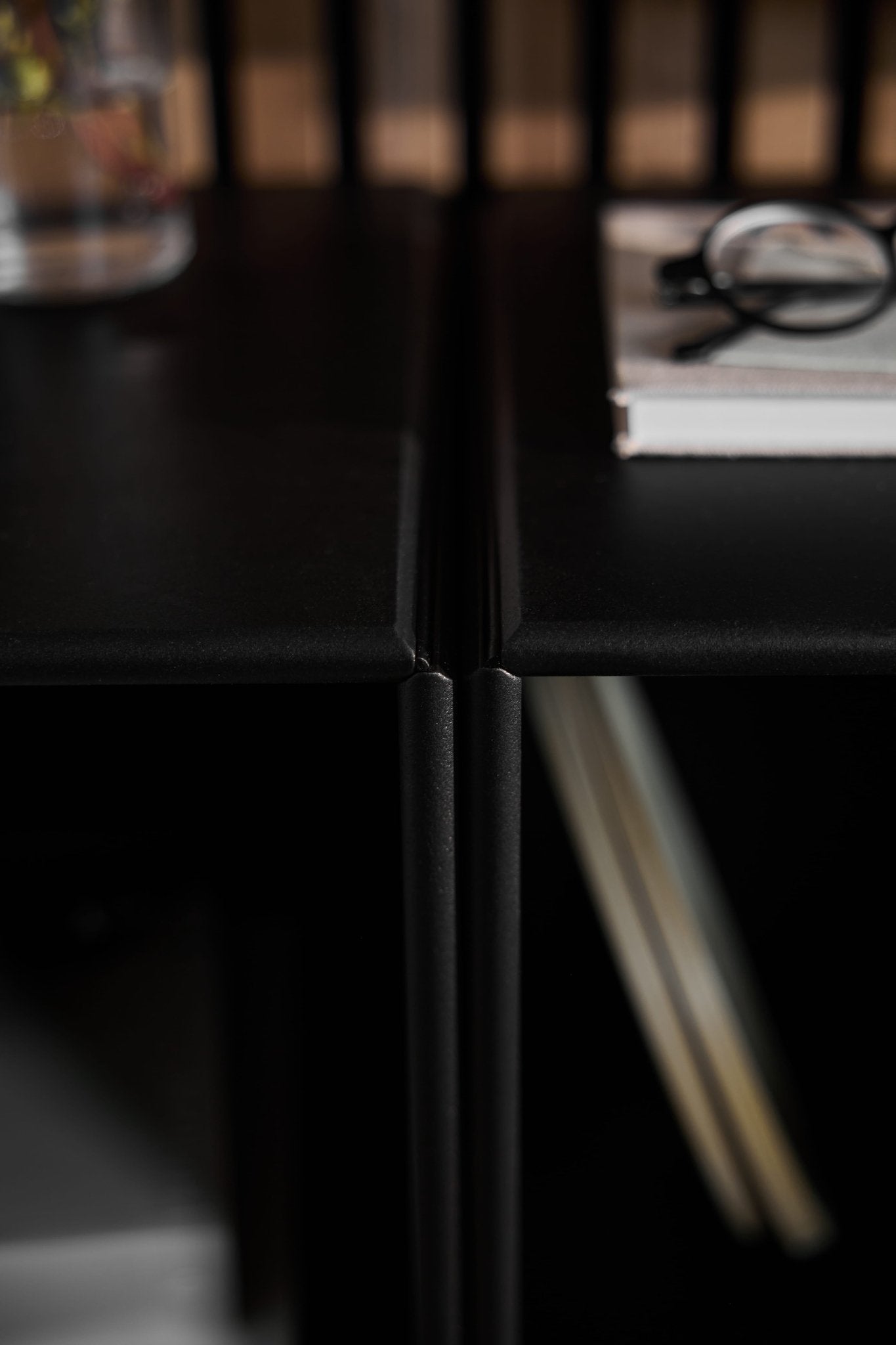 Primer plano de Arka | Armario abierto / Panel acústico de madera negro de WoodUpp; vasos y un libro a la derecha, un vaso de agua a la izquierda, estilo de mobiliario danés.