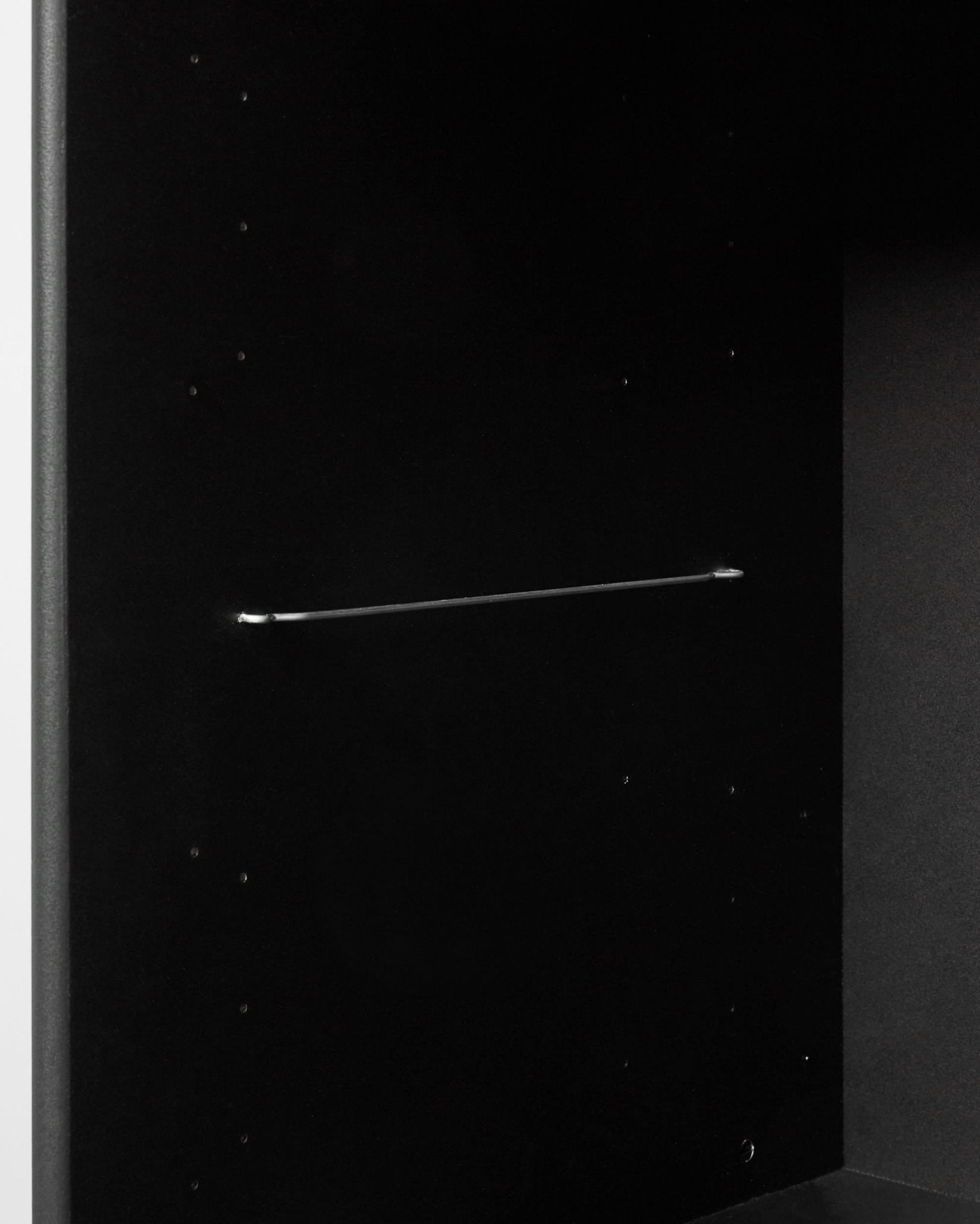 La estantería Arka en negro de WoodUpp, con un interior minimalista en negro y una delgada barra metálica que permite crear estantes modulares de inspiración nórdica.