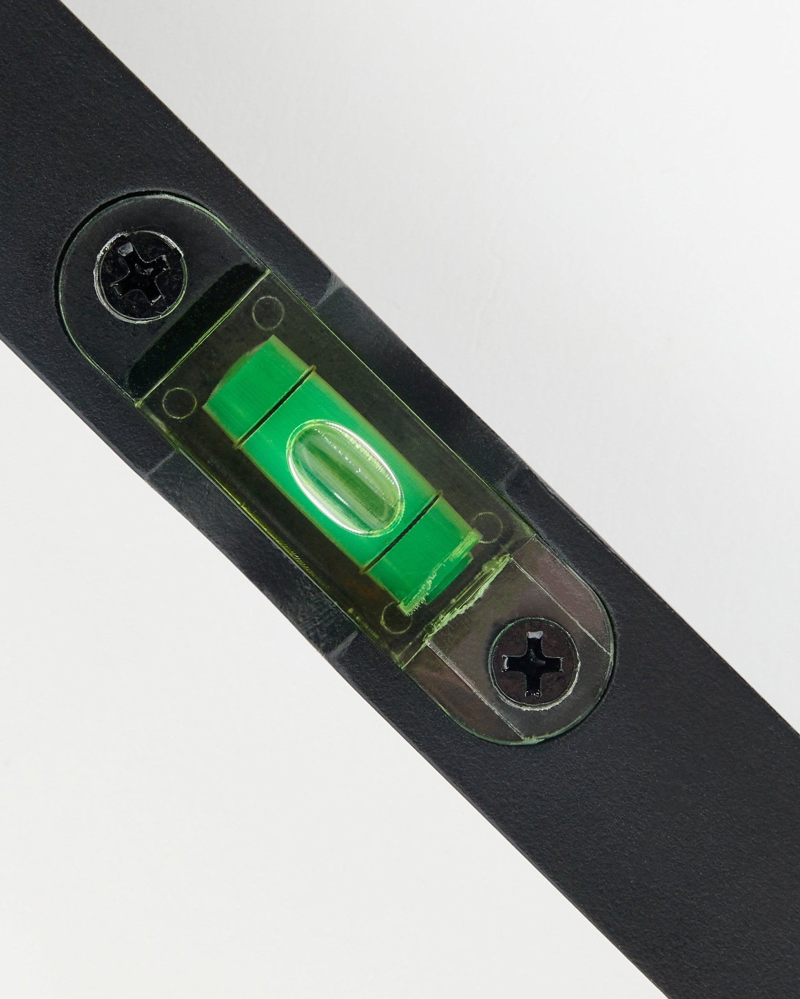 Primer plano de un nivel de burbuja WoodUpp black (15 x 3,2 cm) con vial verde, usado para una instalación precisa de paneles acústicos.