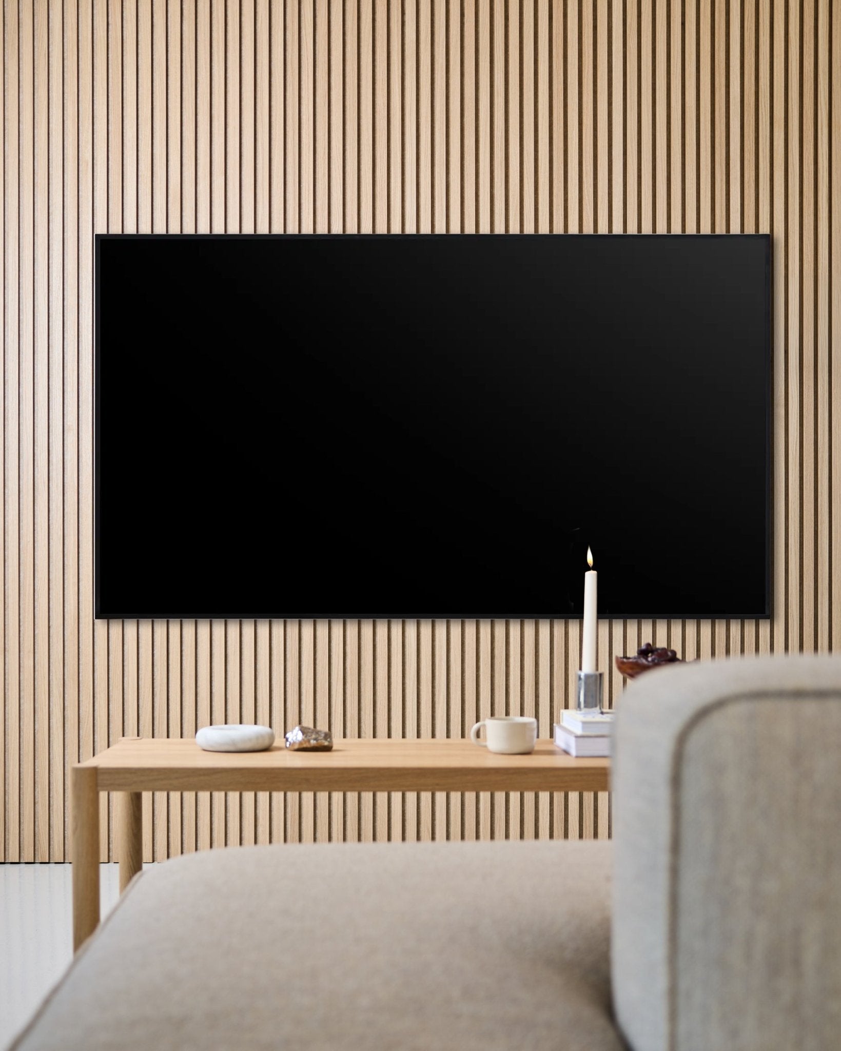 Salón moderno con TV de pantalla plana montada en la pared, pared acústica de lamas de madera Akupanel y mesa de centro de madera para crear un ambiente acogedor.