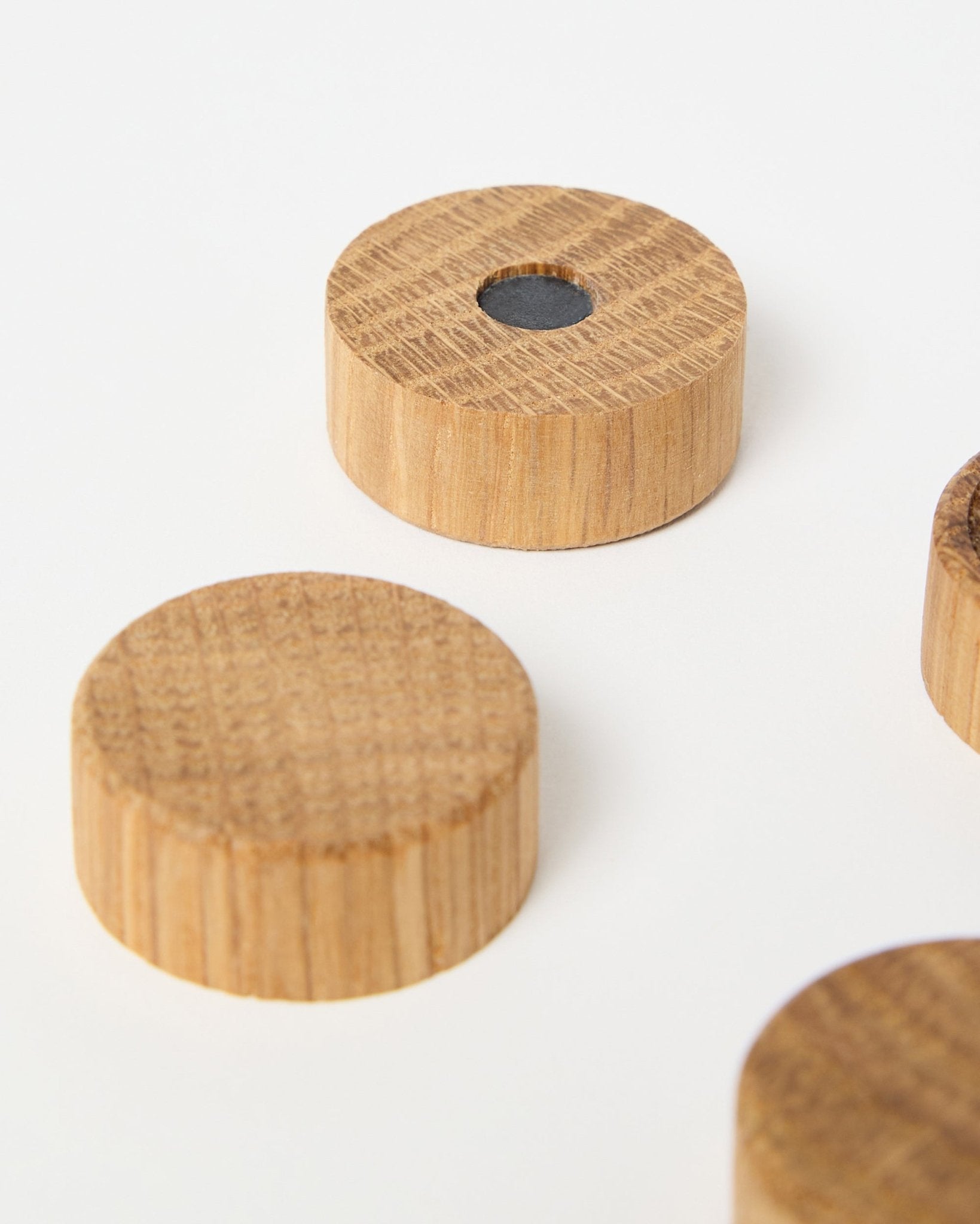 Set de cuatro imanes de natural oak de WoodUpp, diseñados para usar con los paneles acústicos de madera Akupanel, uno de ellos con un imán central de neodimio para una sujeción extra, presentado sobre fondo blanco.