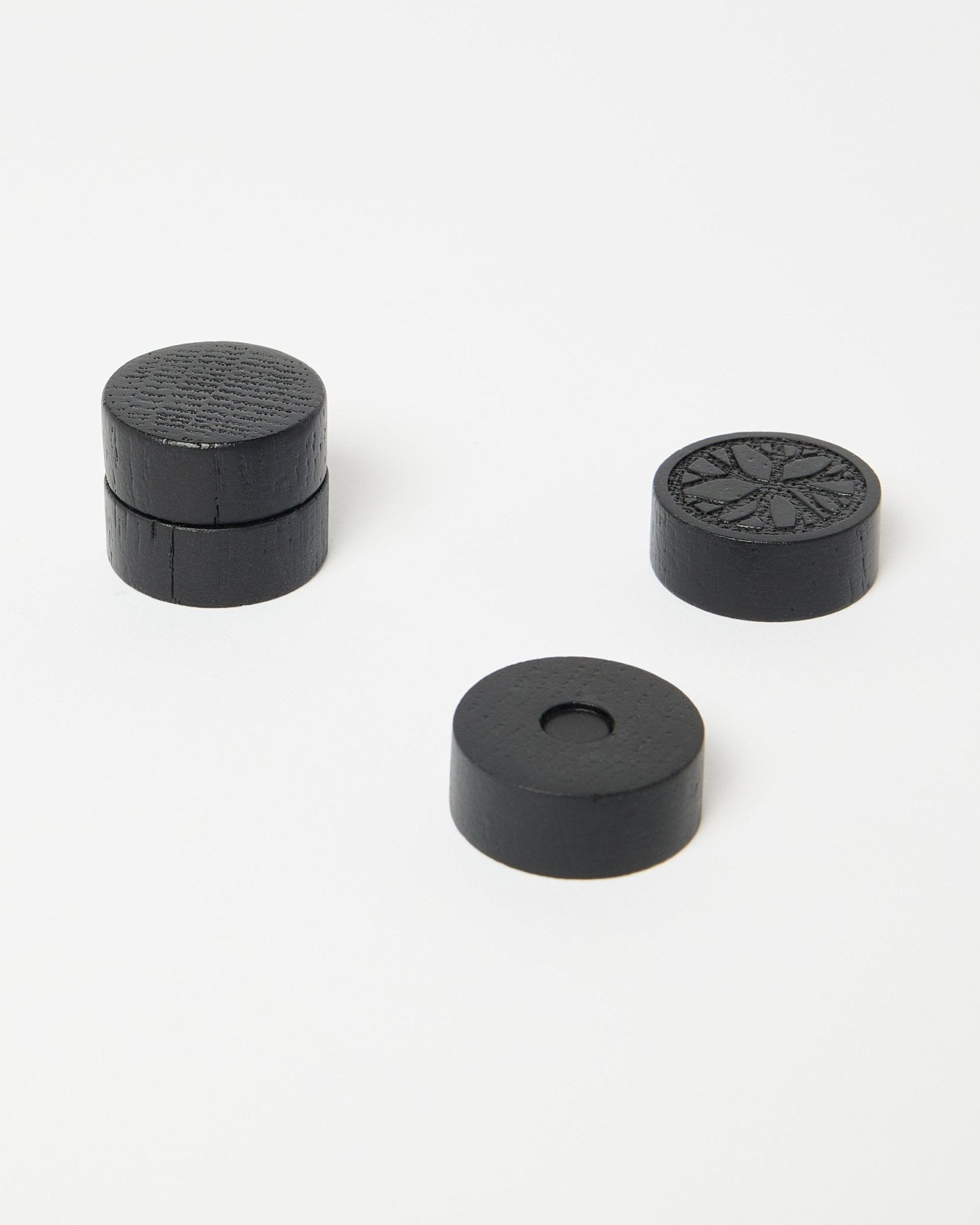 Juego de cuatro imanes Norr black oak de WoodUpp, parte de la colección de accesorios CREATE, colocados con cuidado sobre una superficie blanca limpia.