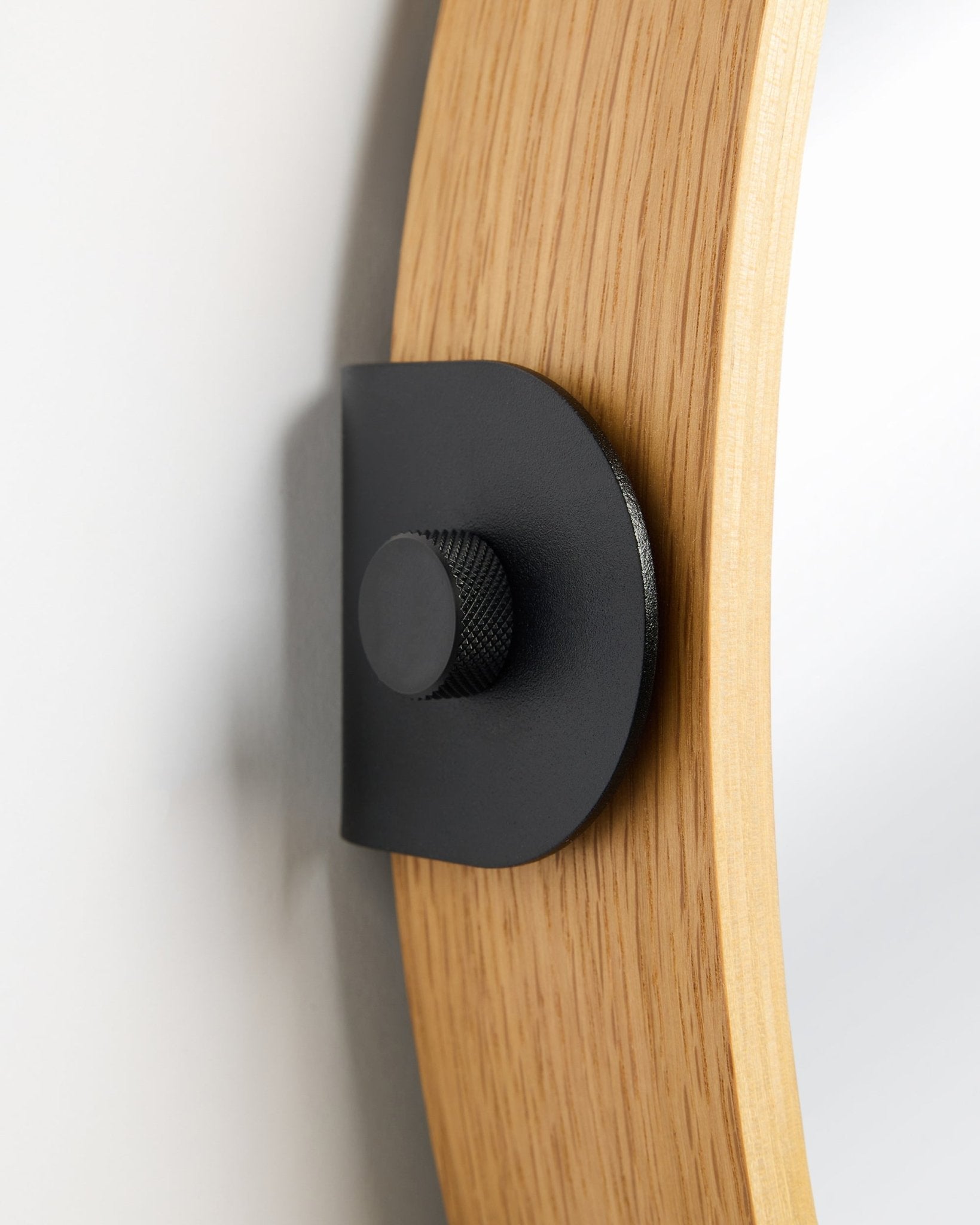 Detalle del espejo Linn de WoodUpp en Natural Oak, un Panel acústico montado en la pared con un soporte metálico black y un pomo redondo.