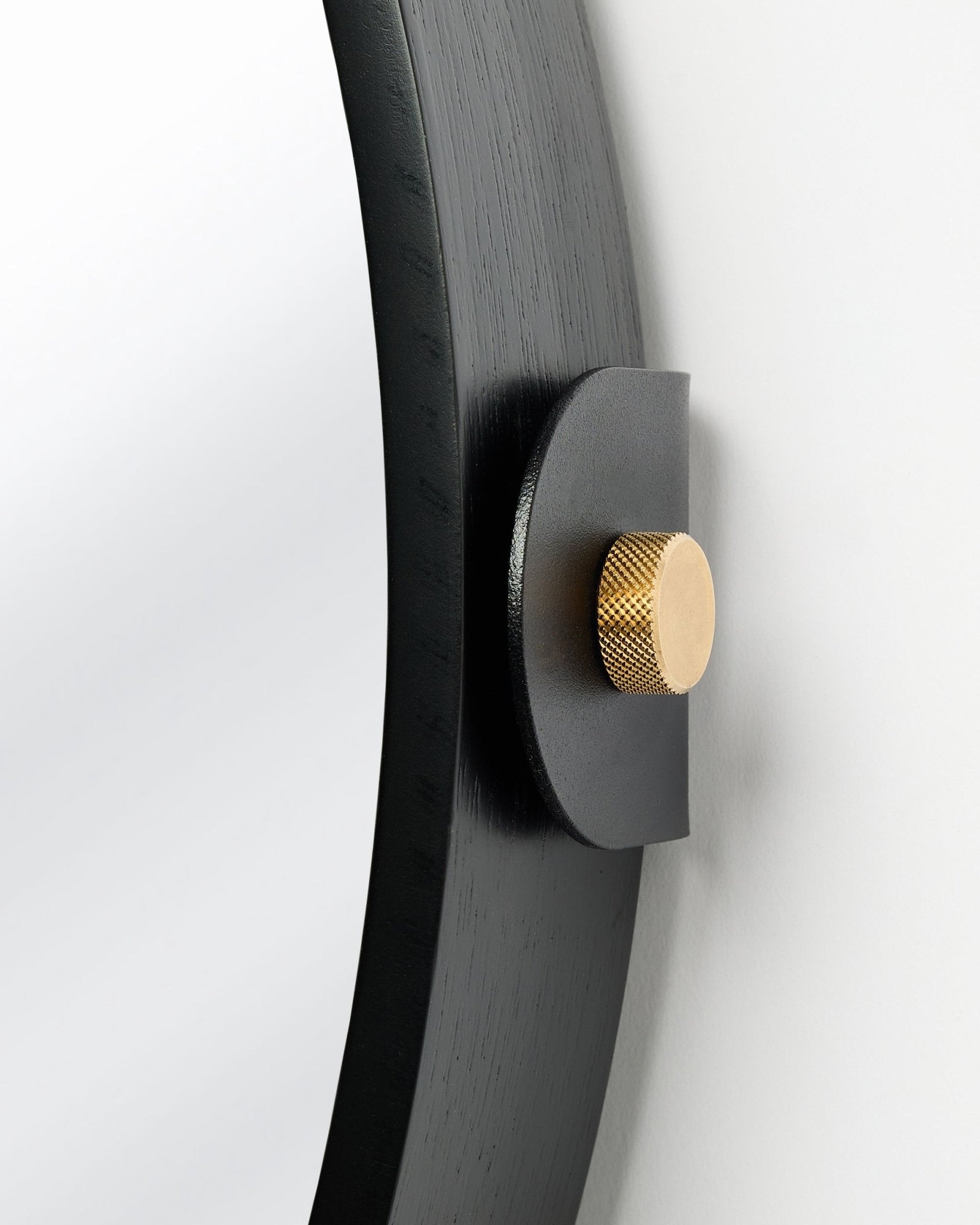 Detalle del Panel acústico Linn | Mirror / Black Oak de WoodUpp, montado en la pared con un pomo dorado y inclinación ajustable.