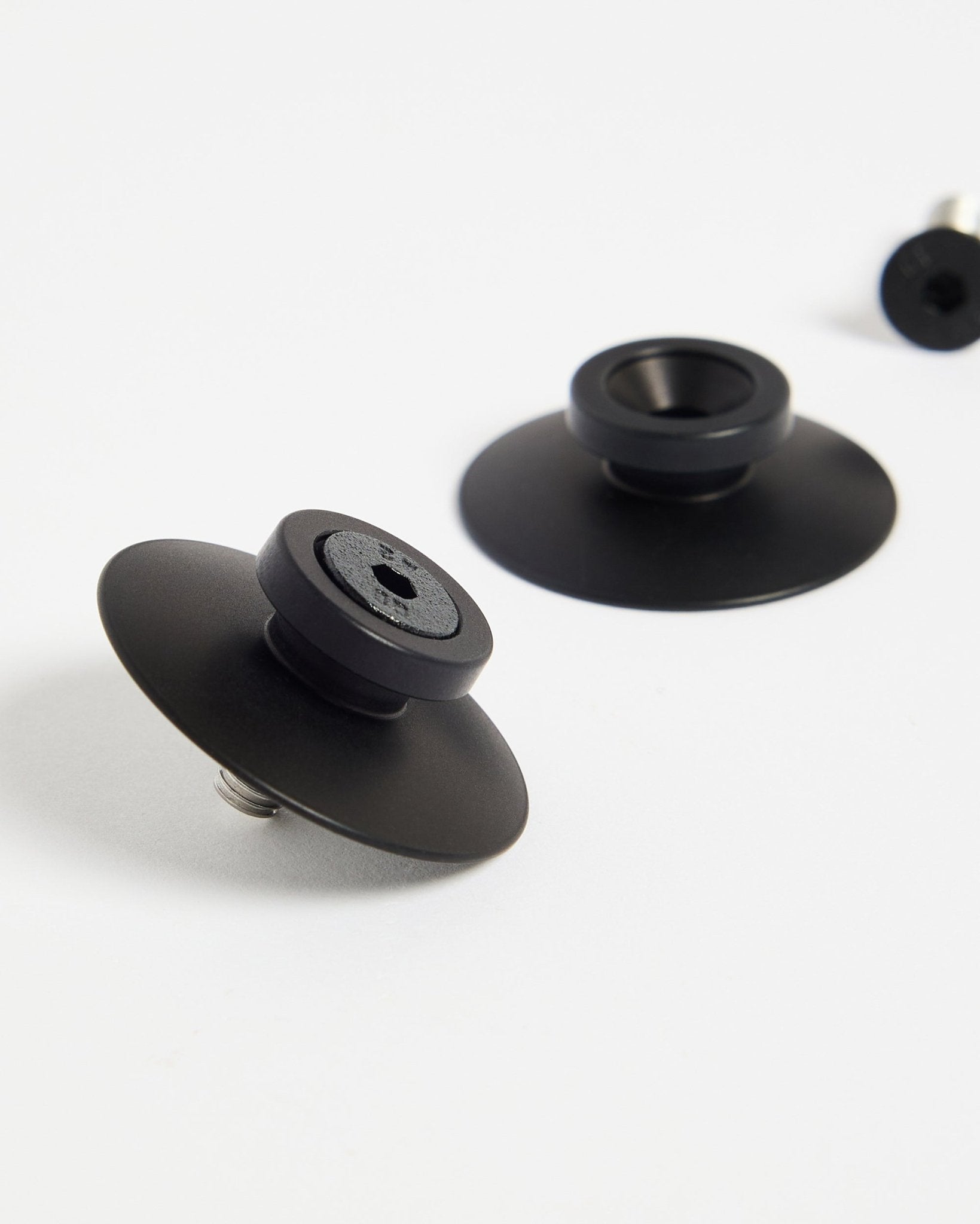 Dos fijaciones WoodUpp Dupps de aluminio black (2 uds.) sobre una superficie blanca, diseñadas para montar con seguridad paneles acústicos o separadores de ambientes.
