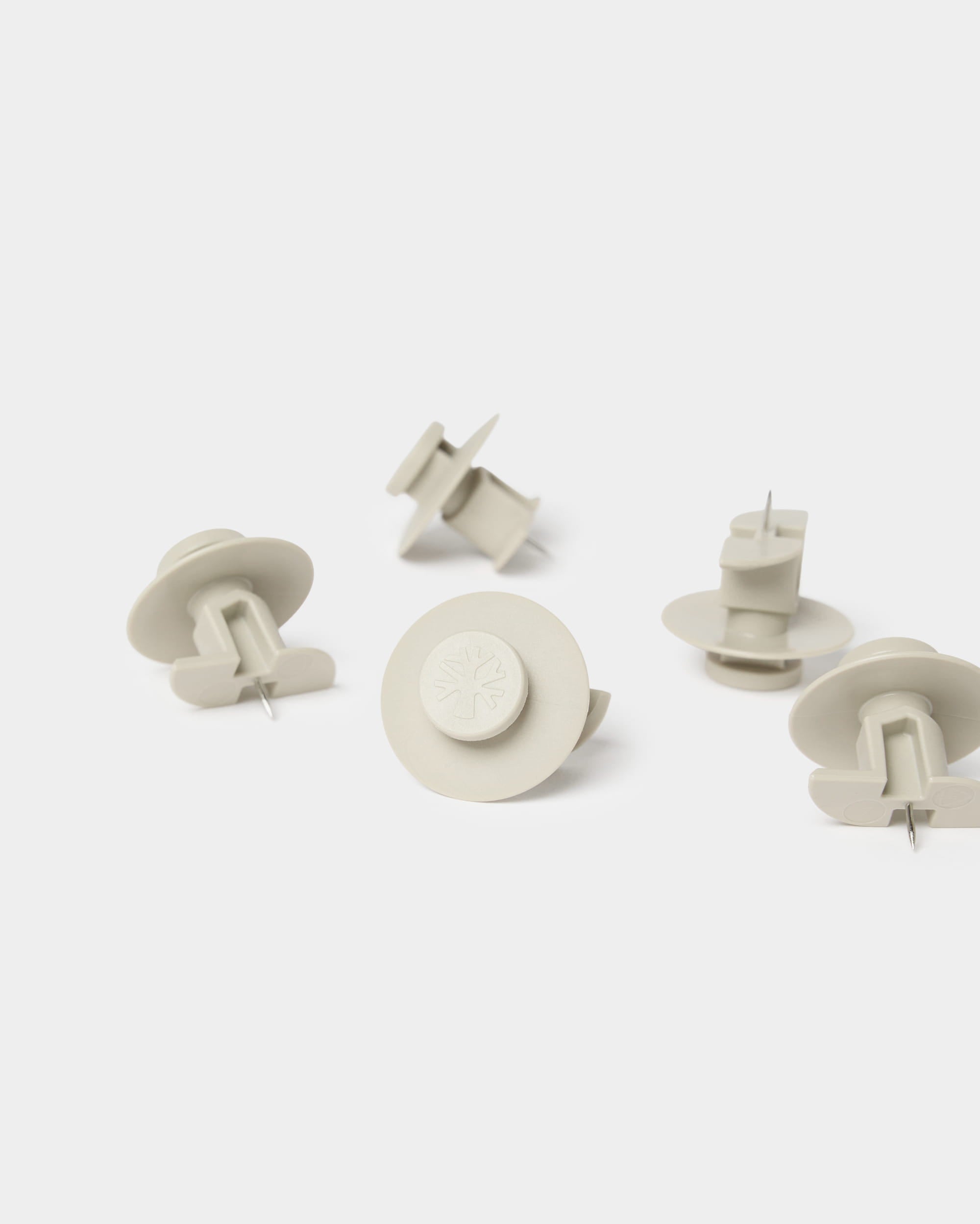Siete chinchetas WoodUpp Dupps de color beige con herramienta incluida, diseñadas para fijar paneles acústicos Akupanel u otras soluciones de pared de WoodUpp.