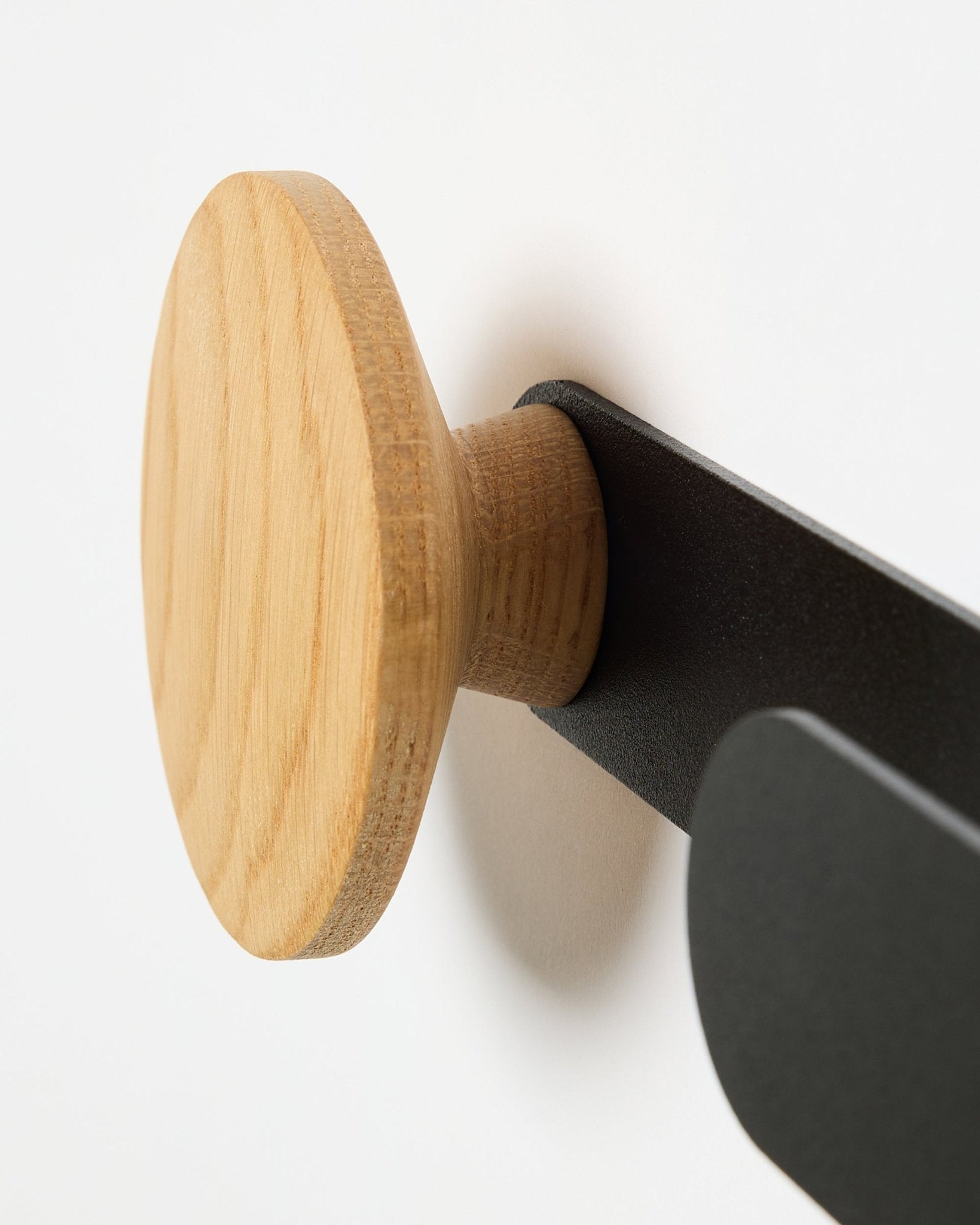 Primer plano del Linn Horizontal Hanger de WoodUpp en natural oak, sobre un soporte metálico black, diseñado para paneles acústicos Akupanel o como gancho de pared funcional.