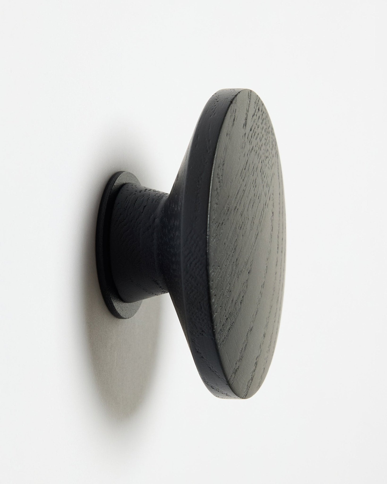 Un Linn | Single Hanger redondo black oak de WoodUpp, diseñado como accesorio para paneles acústicos de madera Akupanel, montado sobre una superficie blanca con una suave sombra hacia la izquierda.