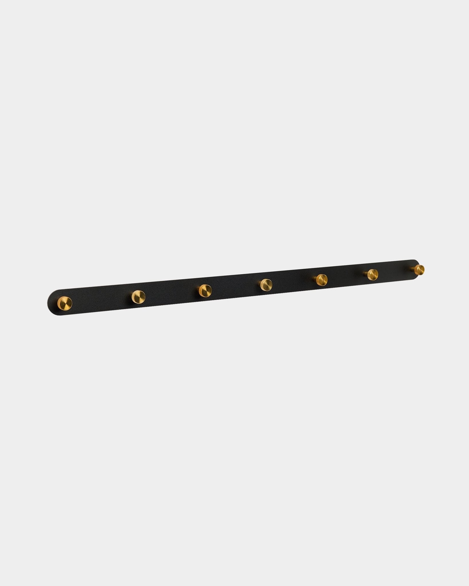 Perchero de pared Norr de WoodUpp con 7 ganchos de brass sobre una black Panel acústico, diseñado como organizador para pasillos y compatible con las colecciones Akupanel.