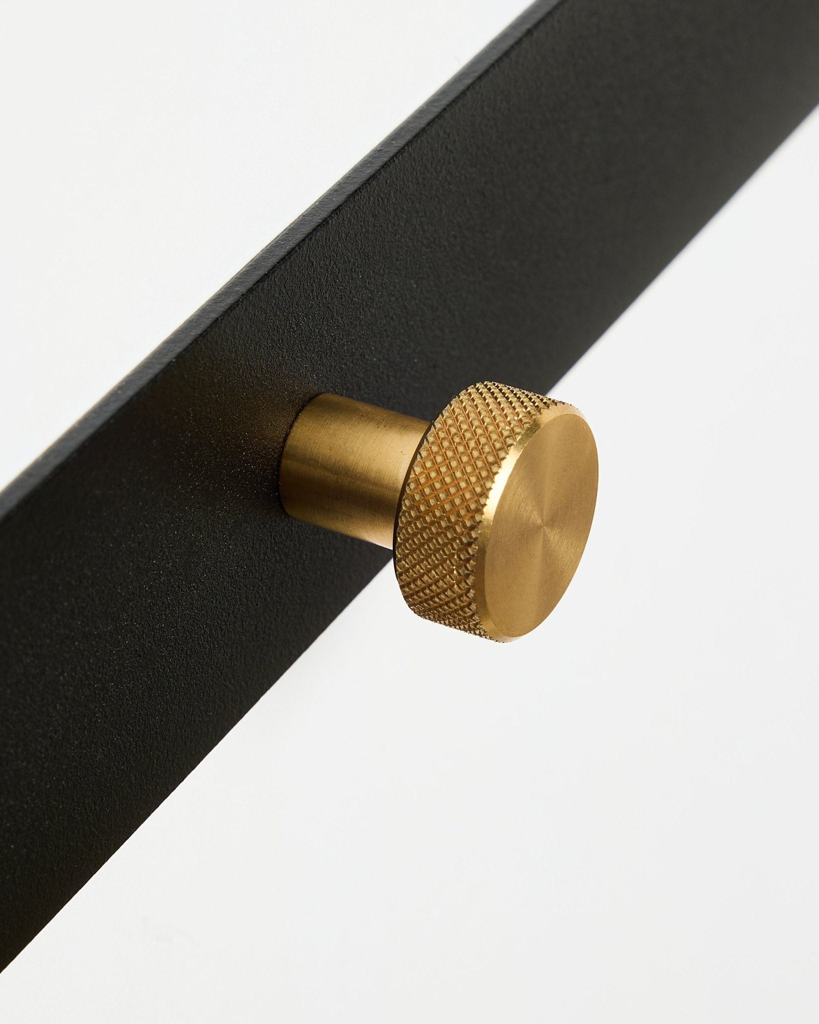 Primer plano del perchero con ganchos Norr X5 de WoodUpp, con steel con recubrimiento en polvo black y pomos redondos texturizados brass, sobre un fondo blanco.
