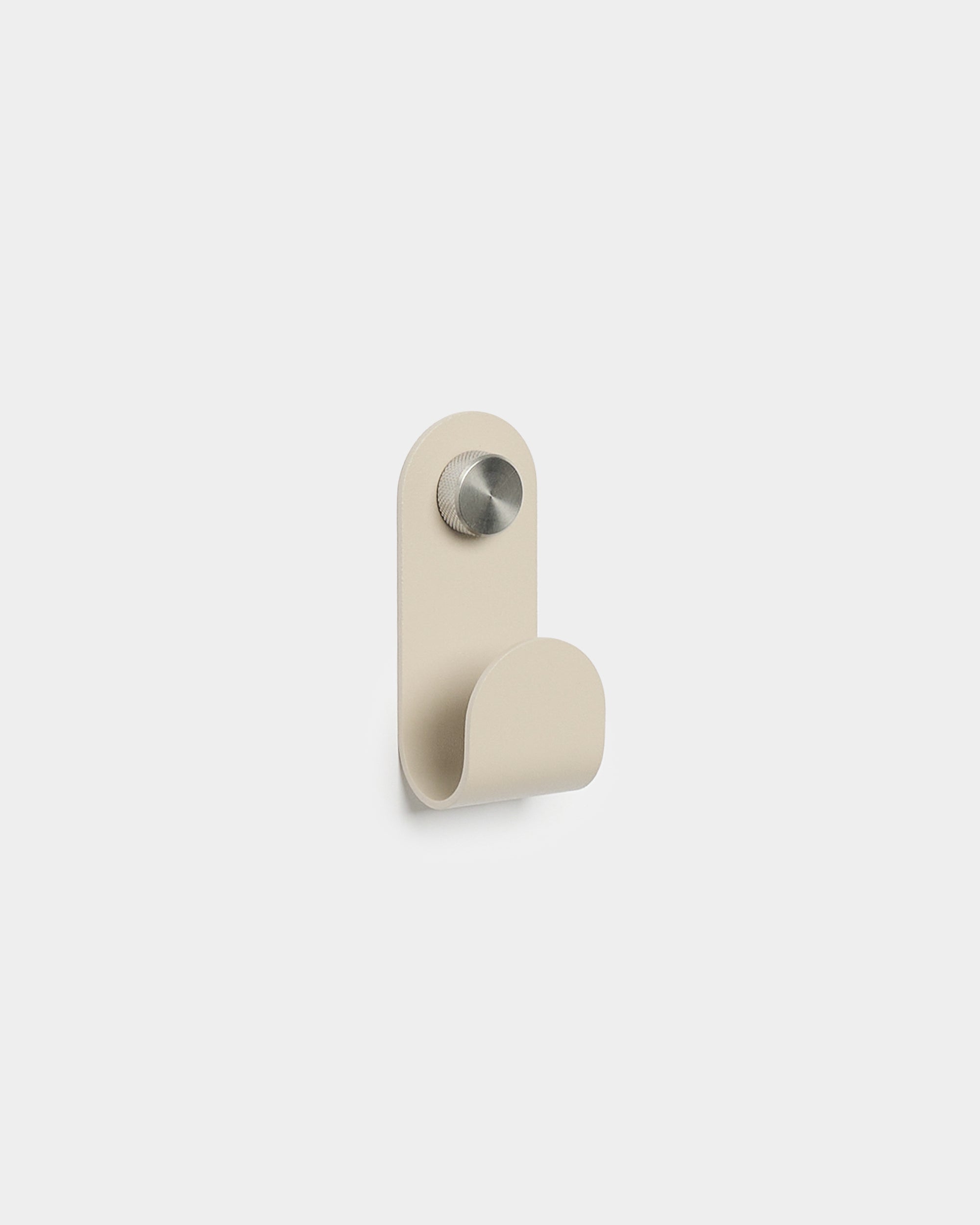 WoodUpp Norr Single Hanger en beige con una forma curva minimalista y acabado de metal cepillado, diseñado como accesorio para ganchos de pared compactos Akupanel.