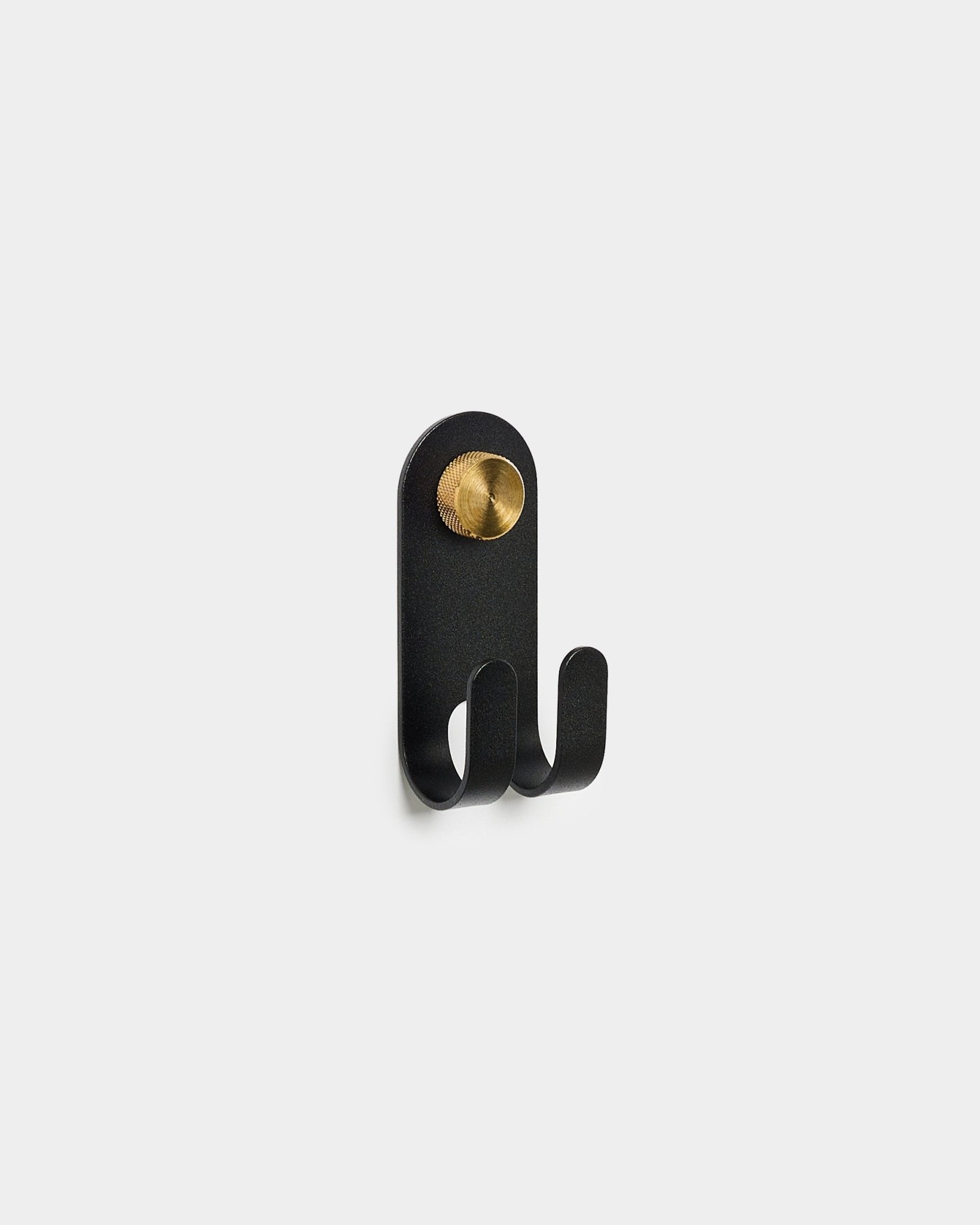 WoodUpp Norr Double Hanger en black, con dos ganchos y un detalle redondo en brass, sobre un fondo blanco liso.