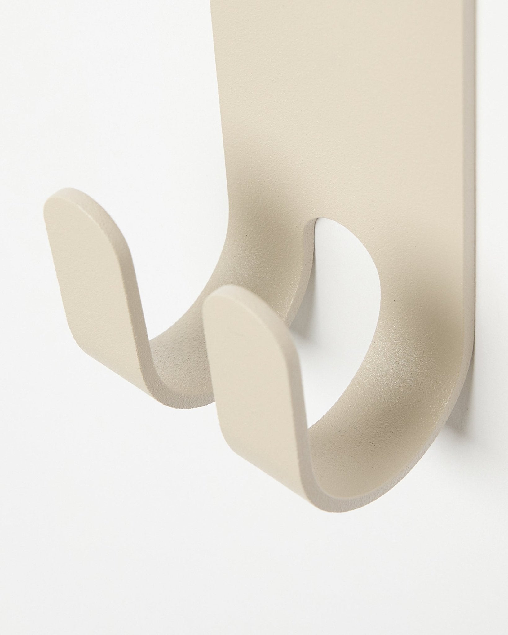 Primer plano del Norr Double Hanger en beige de WoodUpp, un perchero metálico minimalista instalado en un panel de lamas Panel acústico en colored claro.