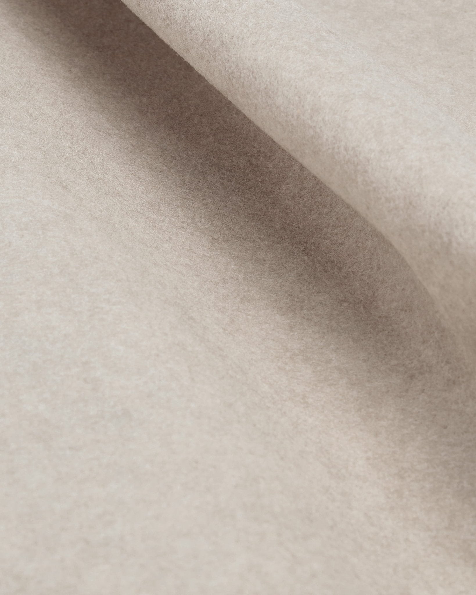 Primer plano de la lámina de fieltro WoodUpp Vigg, de 58 x 241 cm en color beige claro, en el que se aprecian su textura suave y sus sutiles pliegues bajo diferentes condiciones de iluminación.