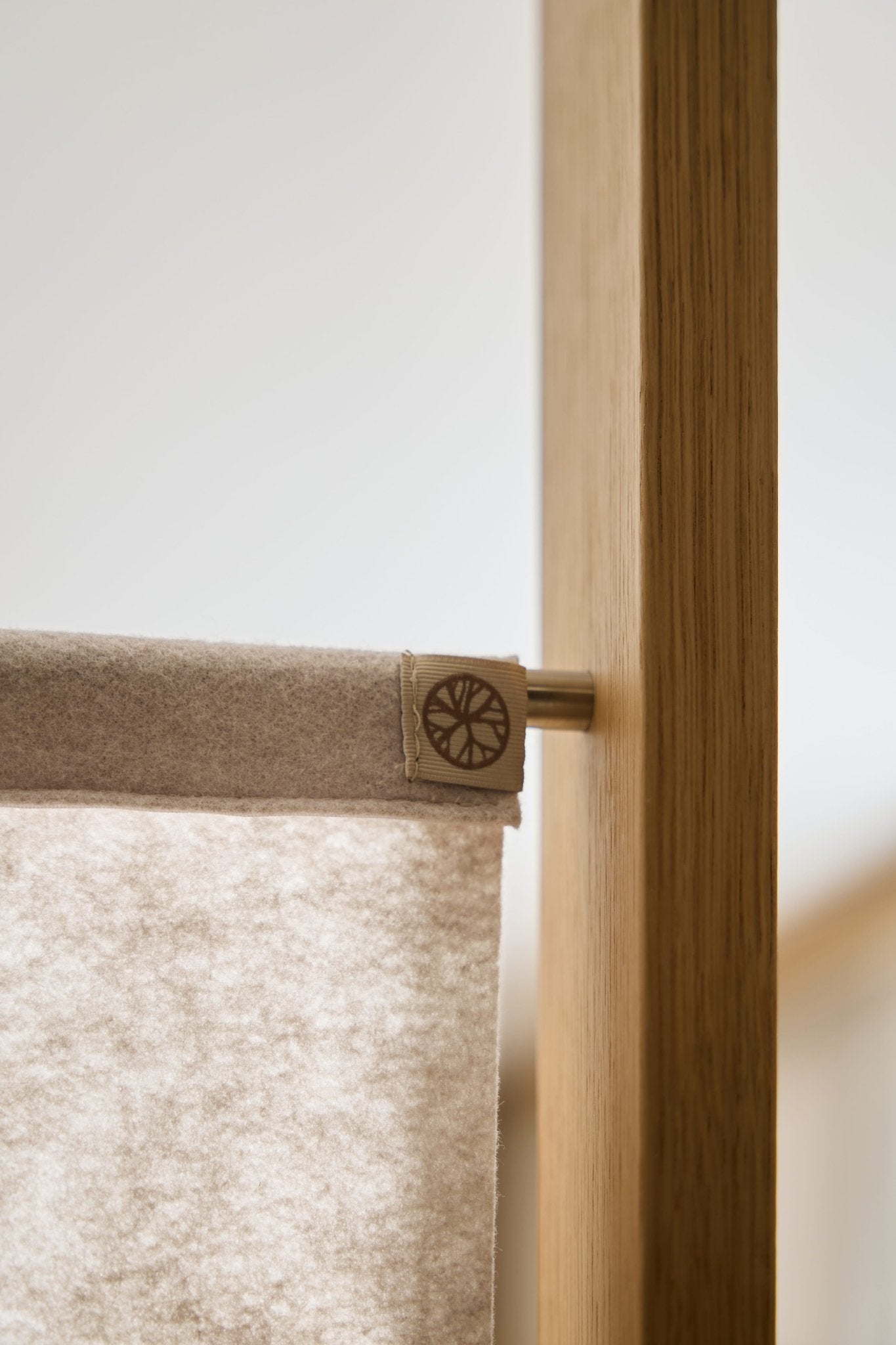 Primer plano de la lámina de fieltro Vigg (58 x 241 cm, beige claro) de WoodUpp, montada sobre una barra metálica y un marco de madera a modo de panel modular separador de espacios.