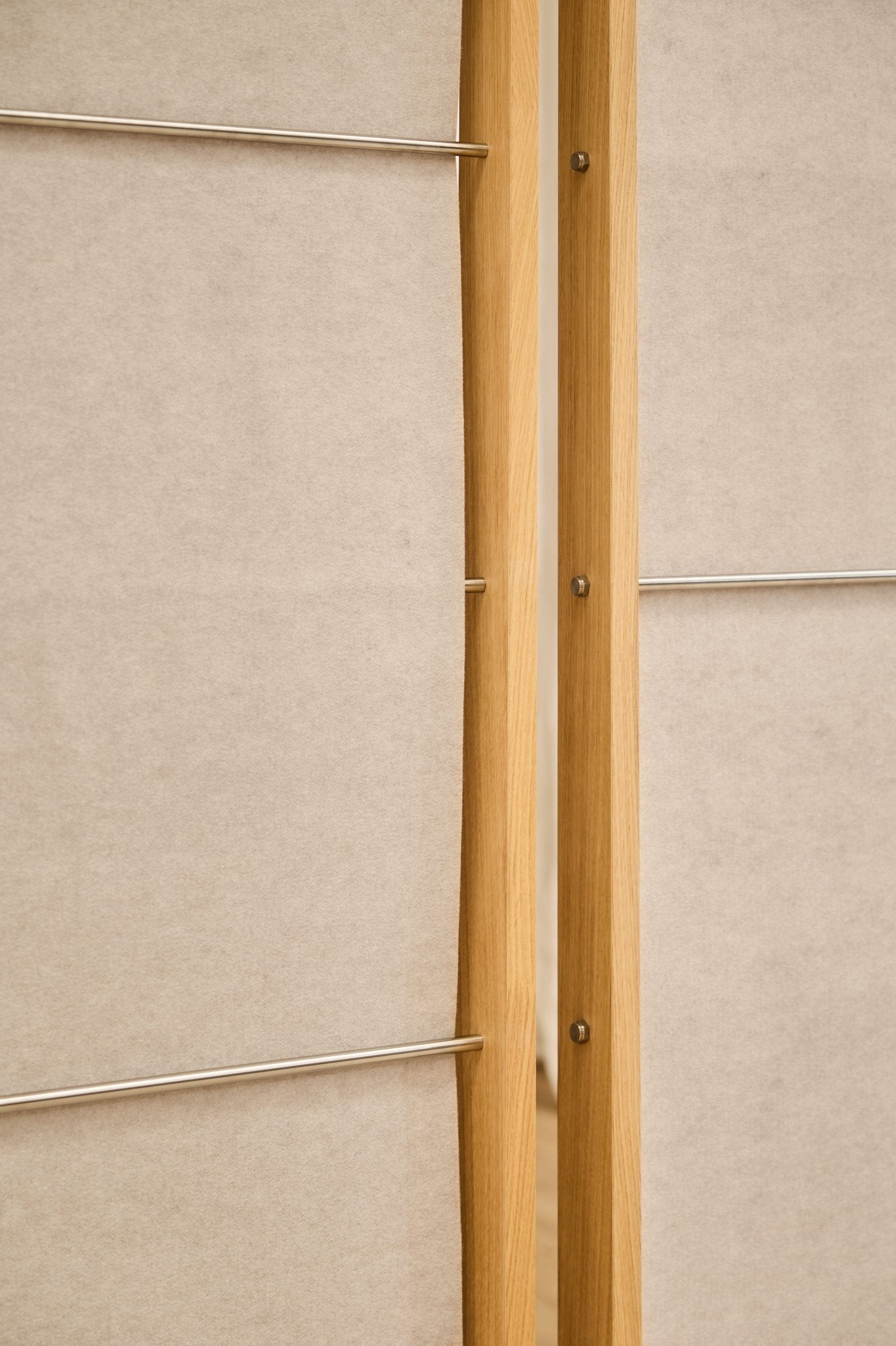 Primer plano de dos paneles acústicos de fieltro WoodUpp Vigg (58 x 241 cm, beige claro), separados por un estrecho espacio, ideales como separadores de ambientes minimalistas.