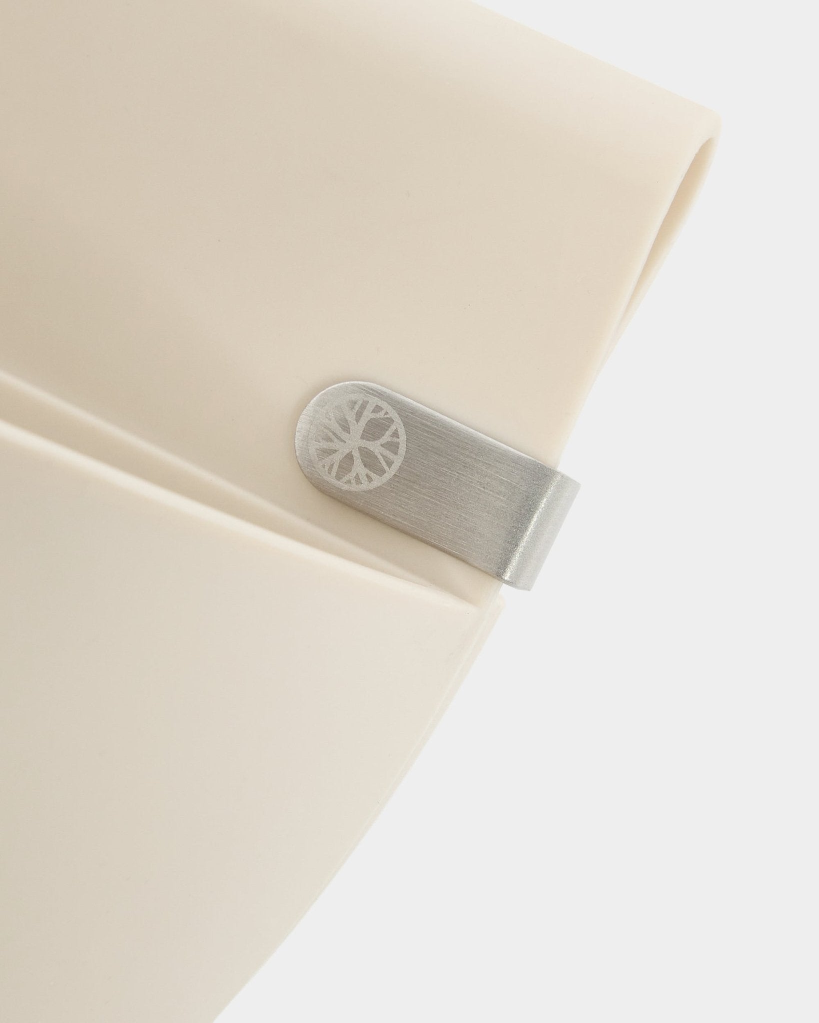 Primer plano de un panel WoodUpp Gro | Soft Pocket / BM2 (4 l) en color claro beige, con clip metálico y detalle de círculo grabado, sobre un fondo blanco liso.