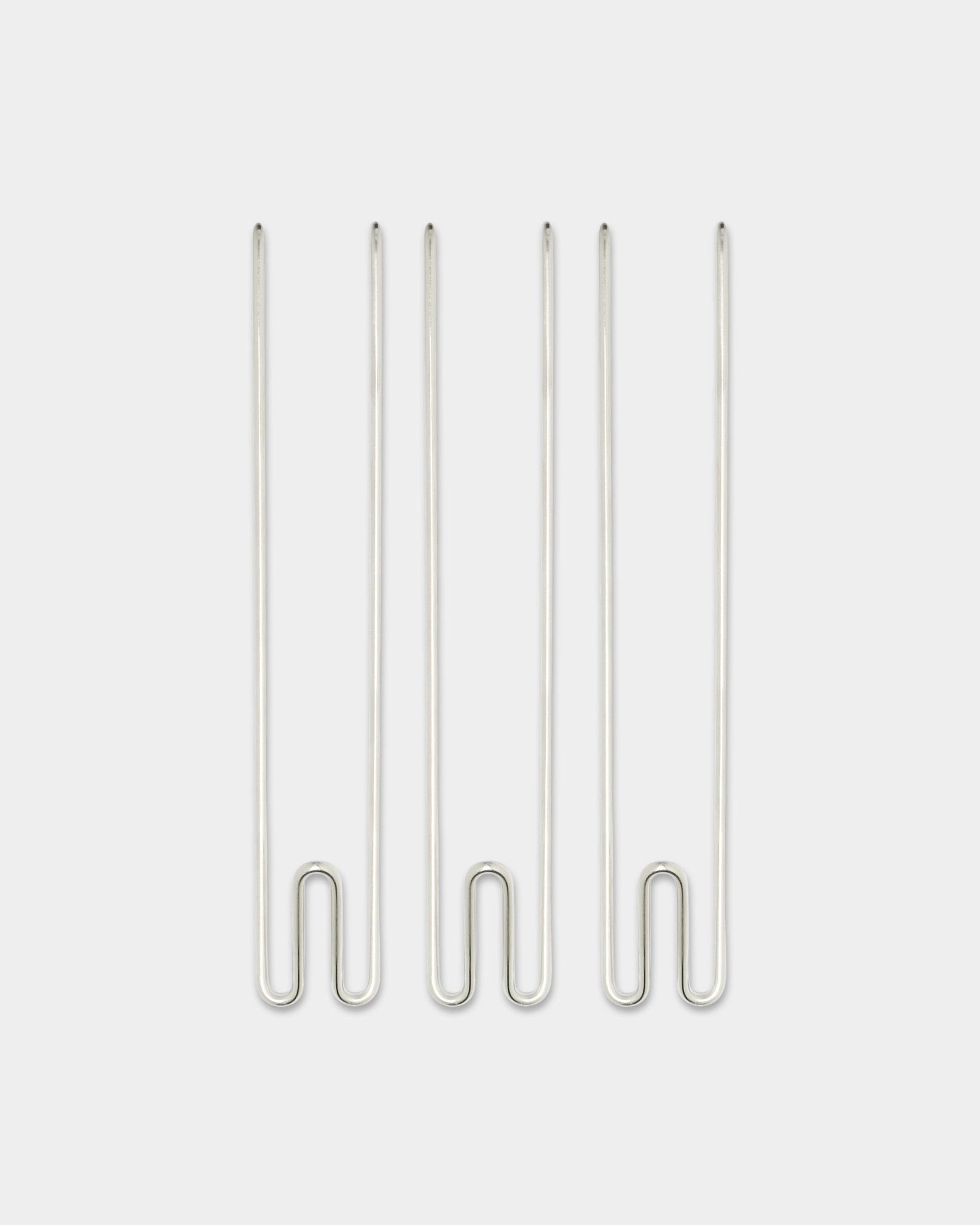 Tres accesorios Alva Wire Hook / BM1 de WoodUpp, ganchos largos de acero inoxidable steel colocados en vertical sobre un fondo blanco liso.