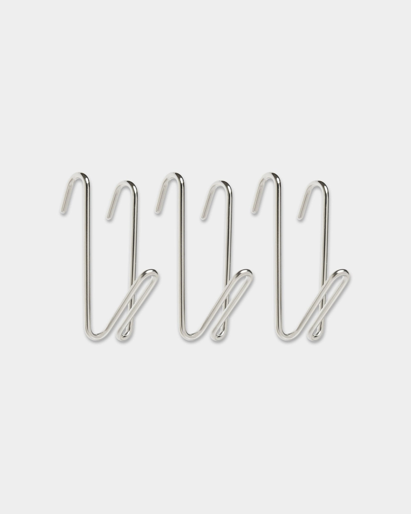 Tres ganchos Alva Wire Hook / BM1, de acero inoxidable steel, en tamaño corto de la colección CREATE de WoodUpp, con diseño en bucle, alineados en una fila sobre un fondo blanco liso.