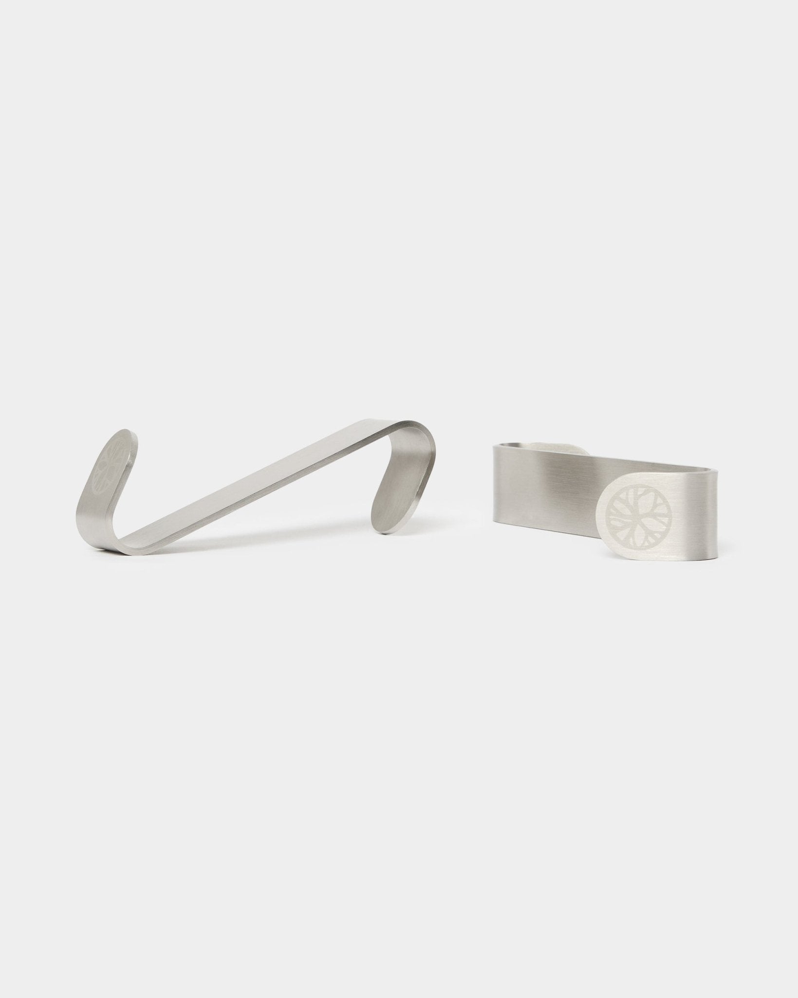 Gancho en S Alva de WoodUpp BM1 y pinzas para billetes BM2, dos accesorios de acero inoxidable steel con diseño de rueda grabado, creados para paneles acústicos nórdicos de madera.