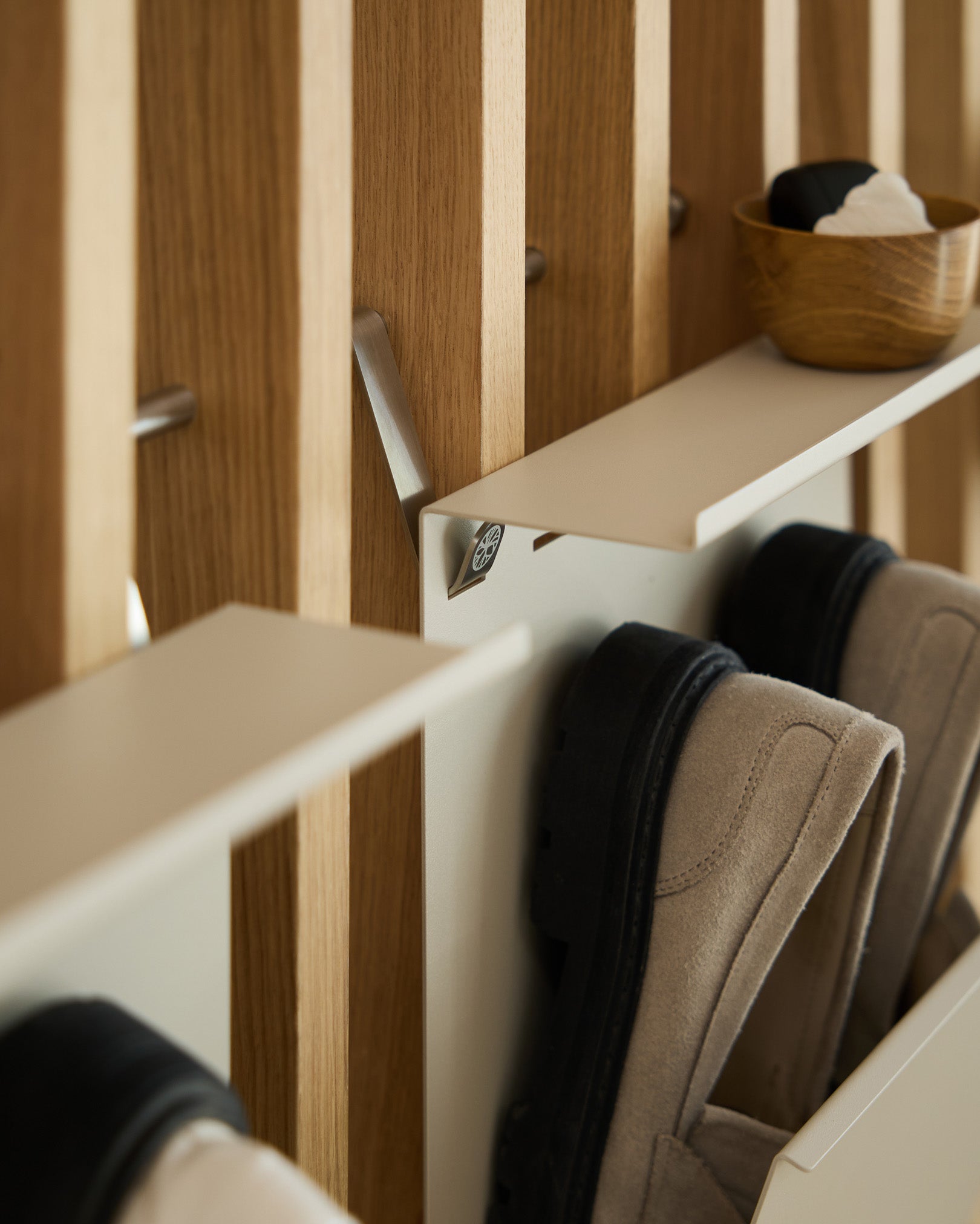 Zapatero minimalista de WoodUpp en beige con steel con recubrimiento en polvo, montado sobre un panel de lamas nórdico Panel acústico, con un cuenco small para las llaves colocado encima.