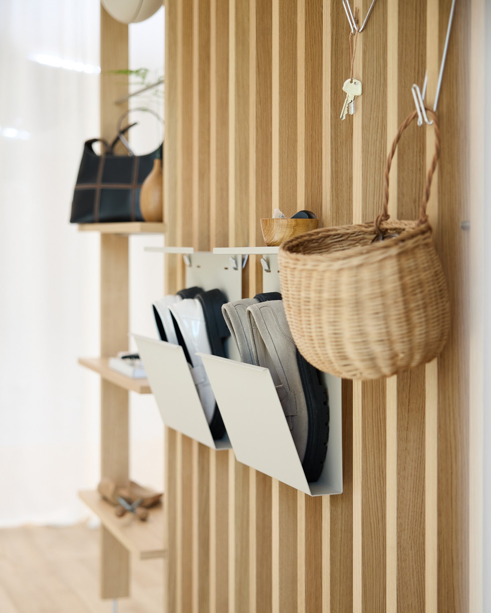 Recibidor moderno con Nell Shoe Storage de WoodUpp en beige, paredes con paneles acústicos de madera Akupanel, ganchos de pared, una cesta colgante y un estante con objetos decorativos.
