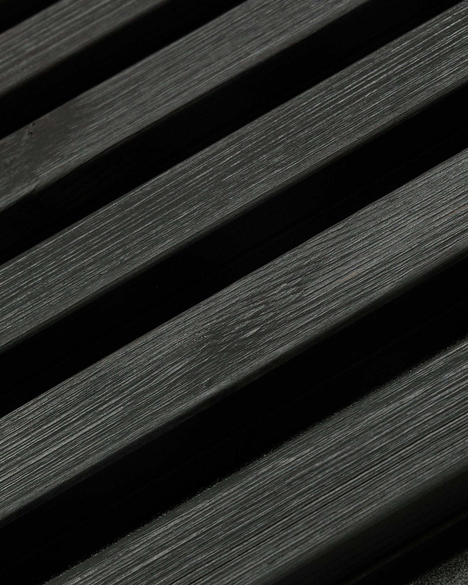 Panel de fachada exterior Aluwood de WoodUpp, Thermowood con acabado black, de 240 x 45,1 cm, con lamas diagonales de abeto nórdico con veta y sombra visibles.