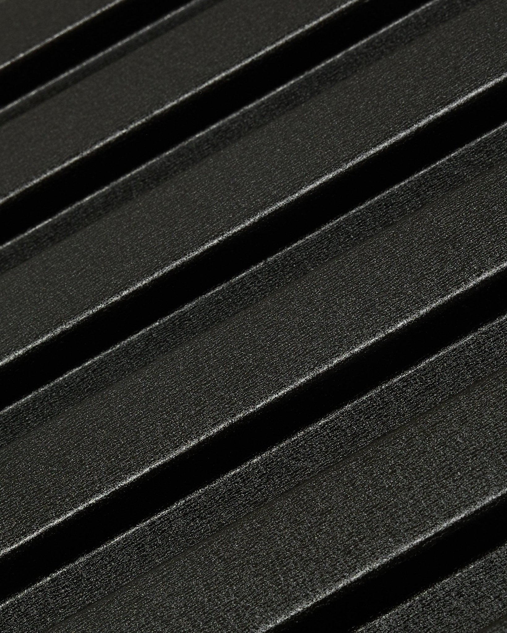 Primer plano del panel de fachada exterior Aluwood de WoodUpp: superficie oscura y texturizada de aluminio reciclado, con relieves diagonales, de 240 x 45,1 cm.