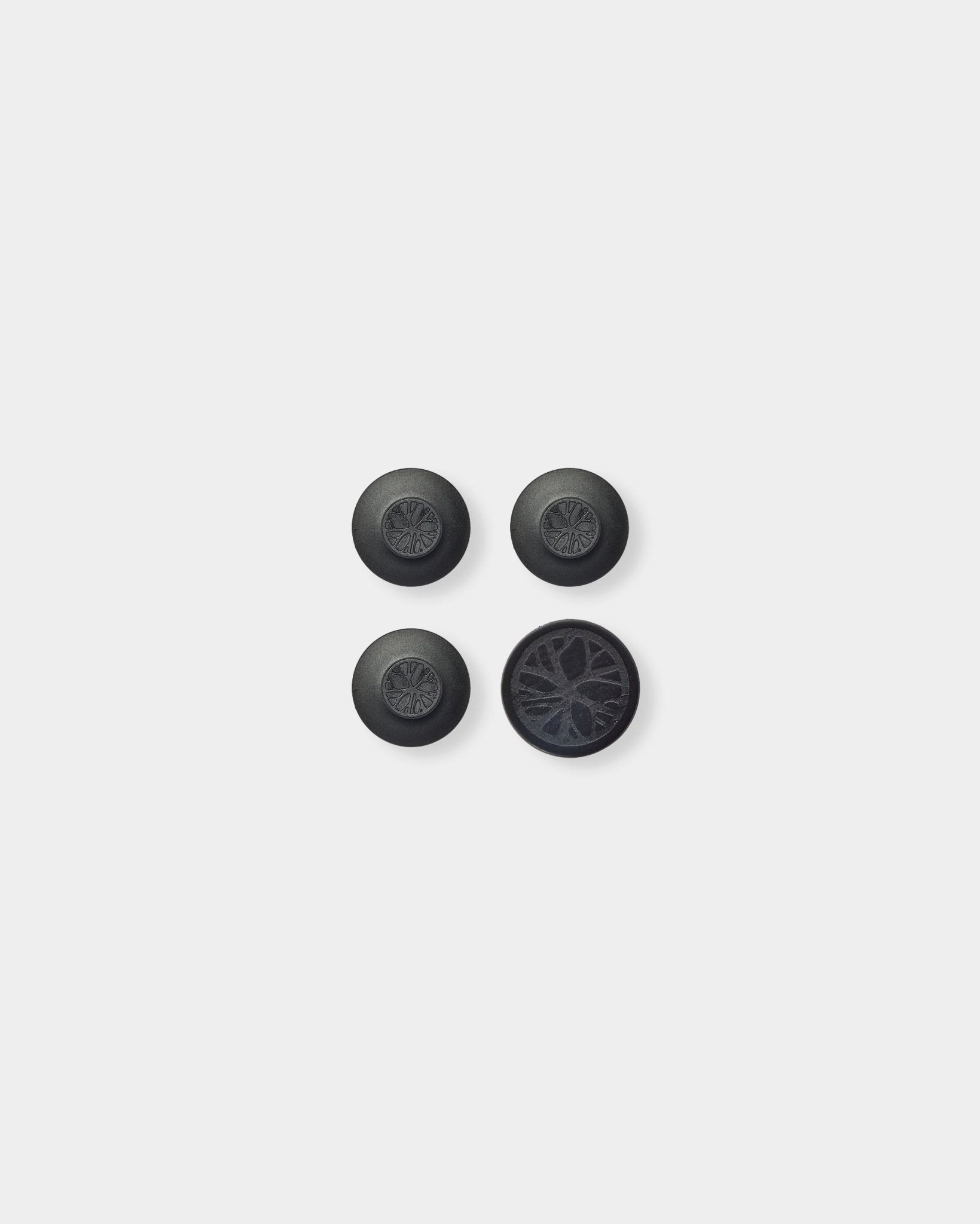 Tres black Dupps redondos y una pieza circular con un detallado patrón acústico de lamas de madera inspirado en el Akupanel nórdico de WoodUpp sobre un fondo gris claro.
