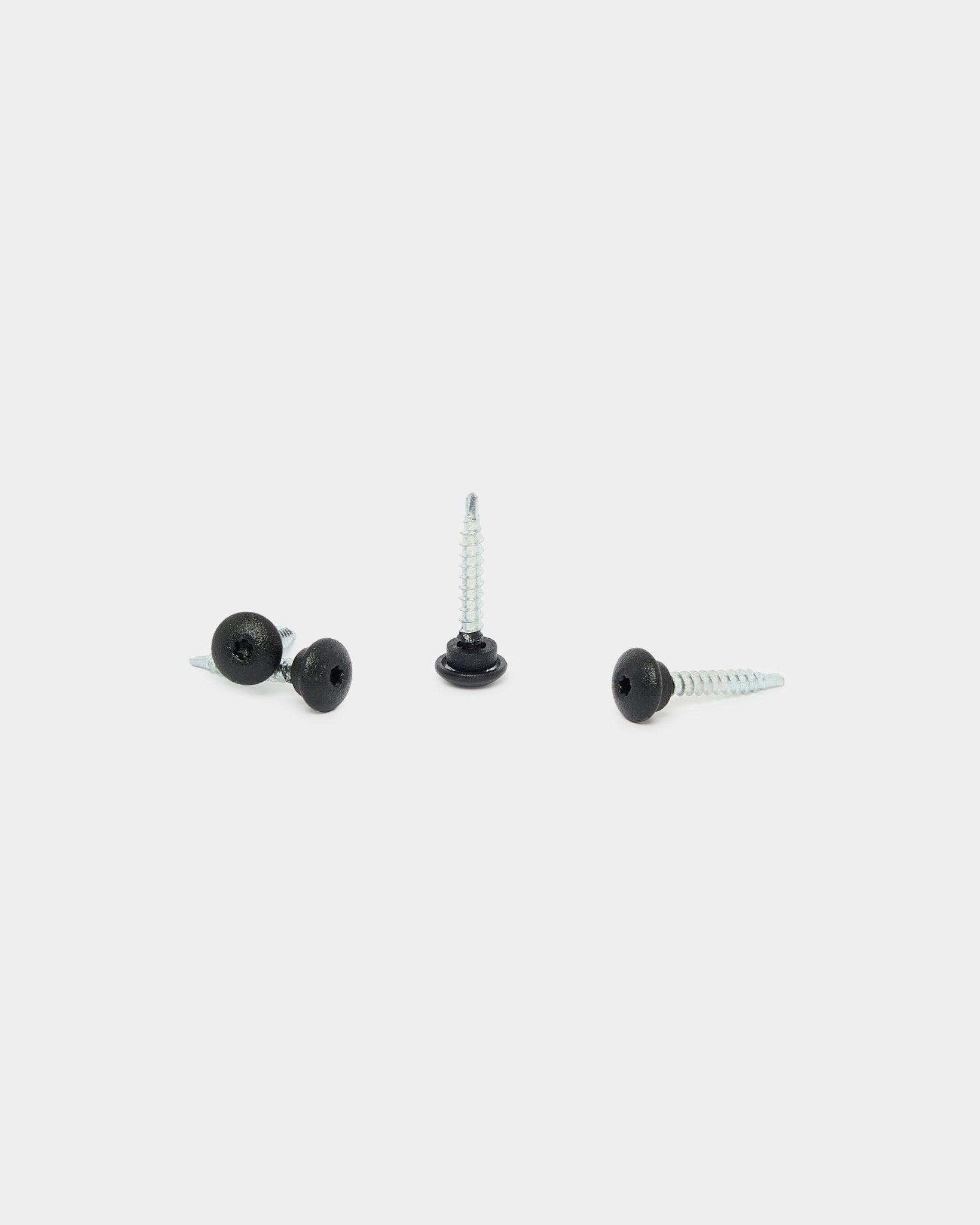 Tres tornillos frontales WoodUpp black 4.8x35 con arandelas Ø9.5, diseñados para paneles acústicos Akupanel, sobre fondo blanco: uno en posición vertical y dos tumbados.