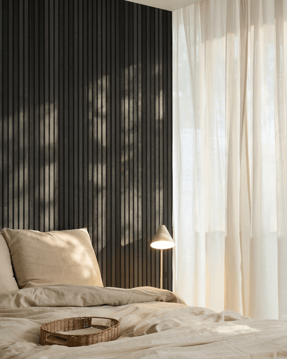 Dormitorio nórdico minimalista con un WoodUpp Akupanel Panel acústico en Ash Black, ropa de cama beige, una bandeja de mimbre y cortinas translúcidas que dejan pasar la luz natural.