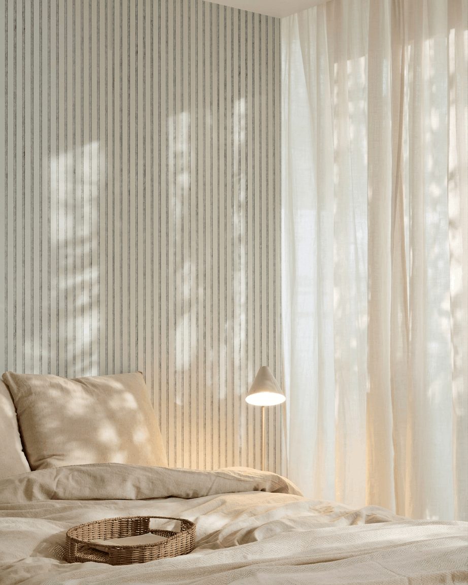 Dormitorio minimalista con ropa de cama beige, una bandeja de mimbre, papel pintado a rayas y un panel acústico de madera Akupanel de WoodUpp en fieltro Snow Grey para la absorción del sonido.