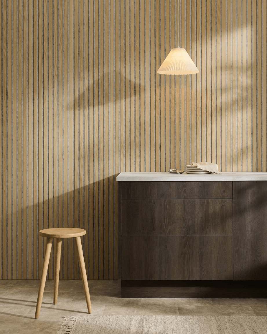Interior nórdico minimalista con un Akupanel Panel acústico de WoodUpp en Classic Oak con fieltro Grey, combinado con un taburete de madera, un armario oscuro y una encimera blanca.