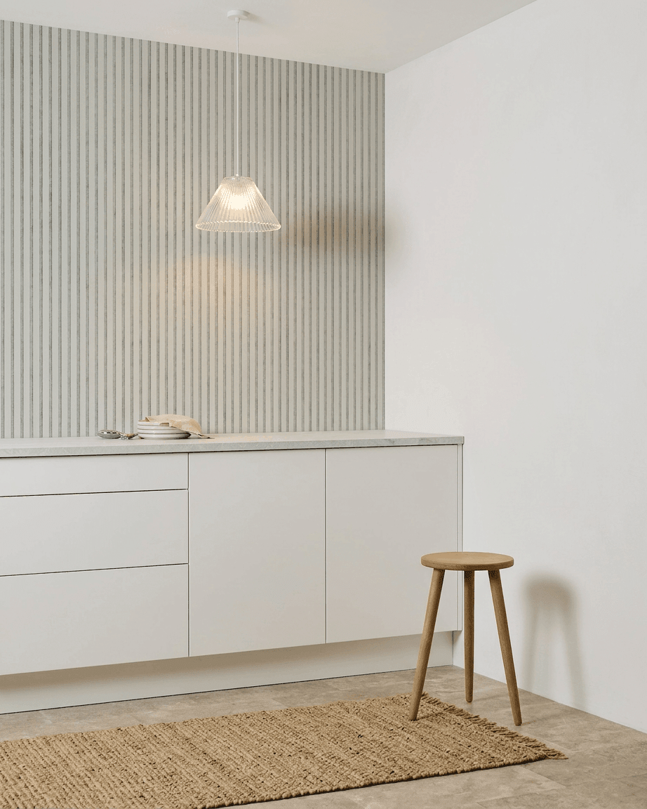 Cocina minimalista con armarios blancos, taburete de madera, alfombra tejida y un Akupanel Snow Panel acústico de WoodUpp instalado para la absorción del sonido.