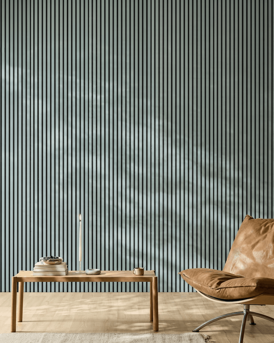 Espacio minimalista con un banco de madera, libros y una silla de cuero brown frente a un WoodUpp Akupanel Panel acústico en color Cloud con fieltro black.