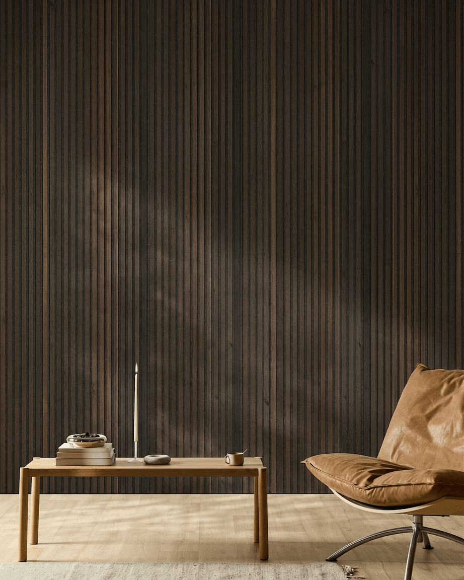 Habitación nórdica minimalista con silla de cuero color canela, mesa de madera, vela y taza, frente a una pared WoodUpp Akupanel Natural Wood Rustic Smoked Oak Panel acústico.
