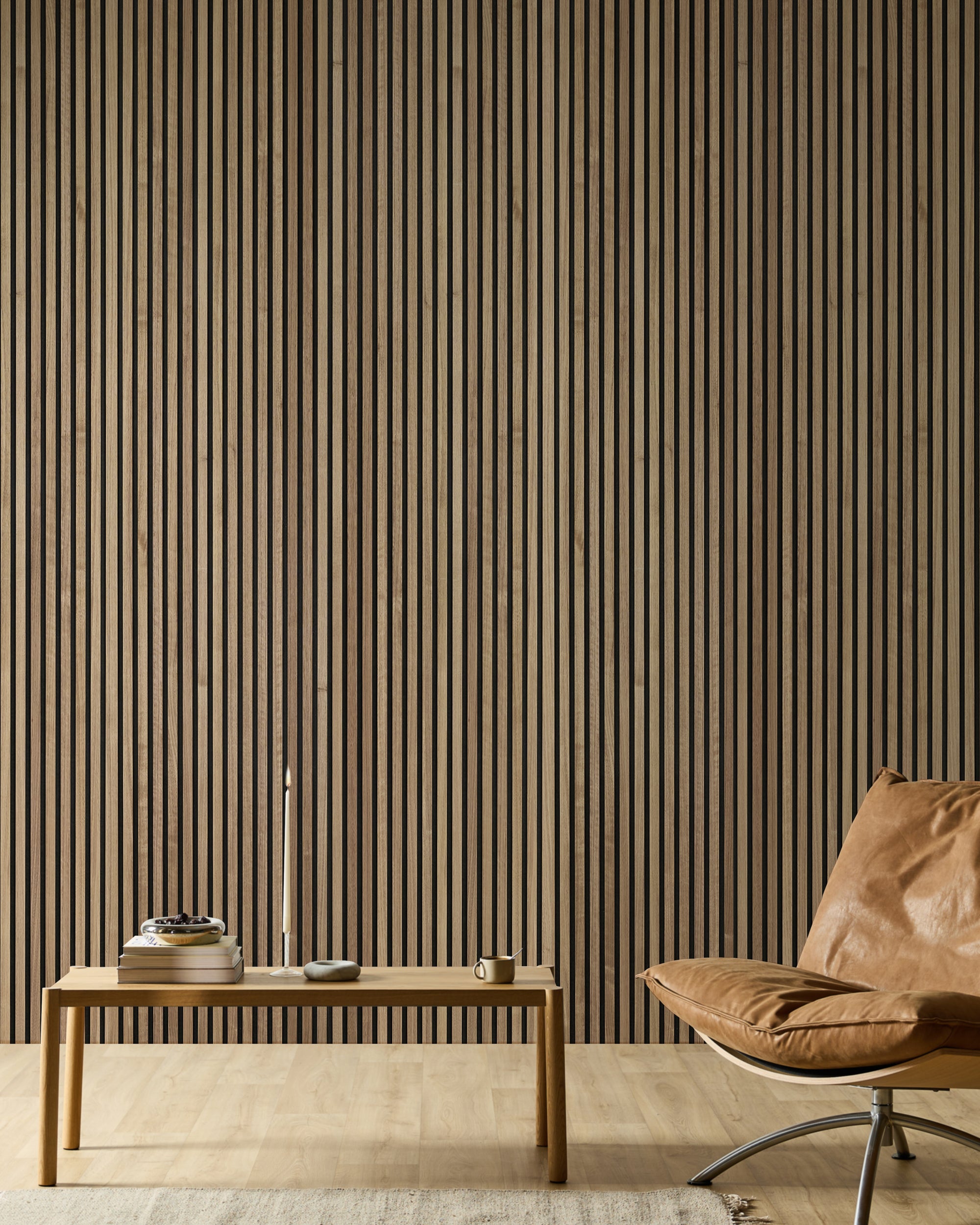 Espacio minimalista con una silla de cuero, un banco de madera, libros, una vela y una moderna pared de acento de madera con lamas acústicas Akupanel en tonos neutros.
