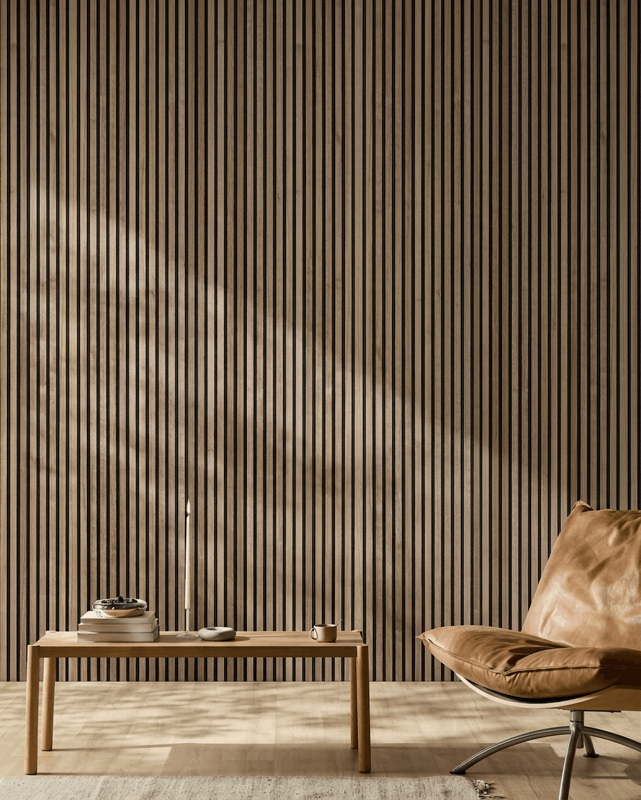 Espacio nórdico minimalista con panel acústico de madera WoodUpp Akupanel en nogal, sillón de cuero tostado y mesa de centro de madera con libros y una vela.
