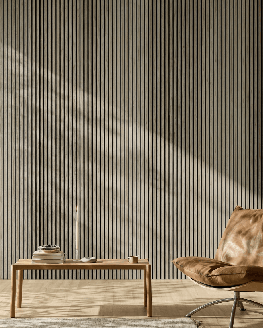 Espacio minimalista con un WoodUpp Akupanel de 240x60 cm en roble envejecido con fieltro black, banco de madera, libros, vela, taza y silla de cuero color canela.