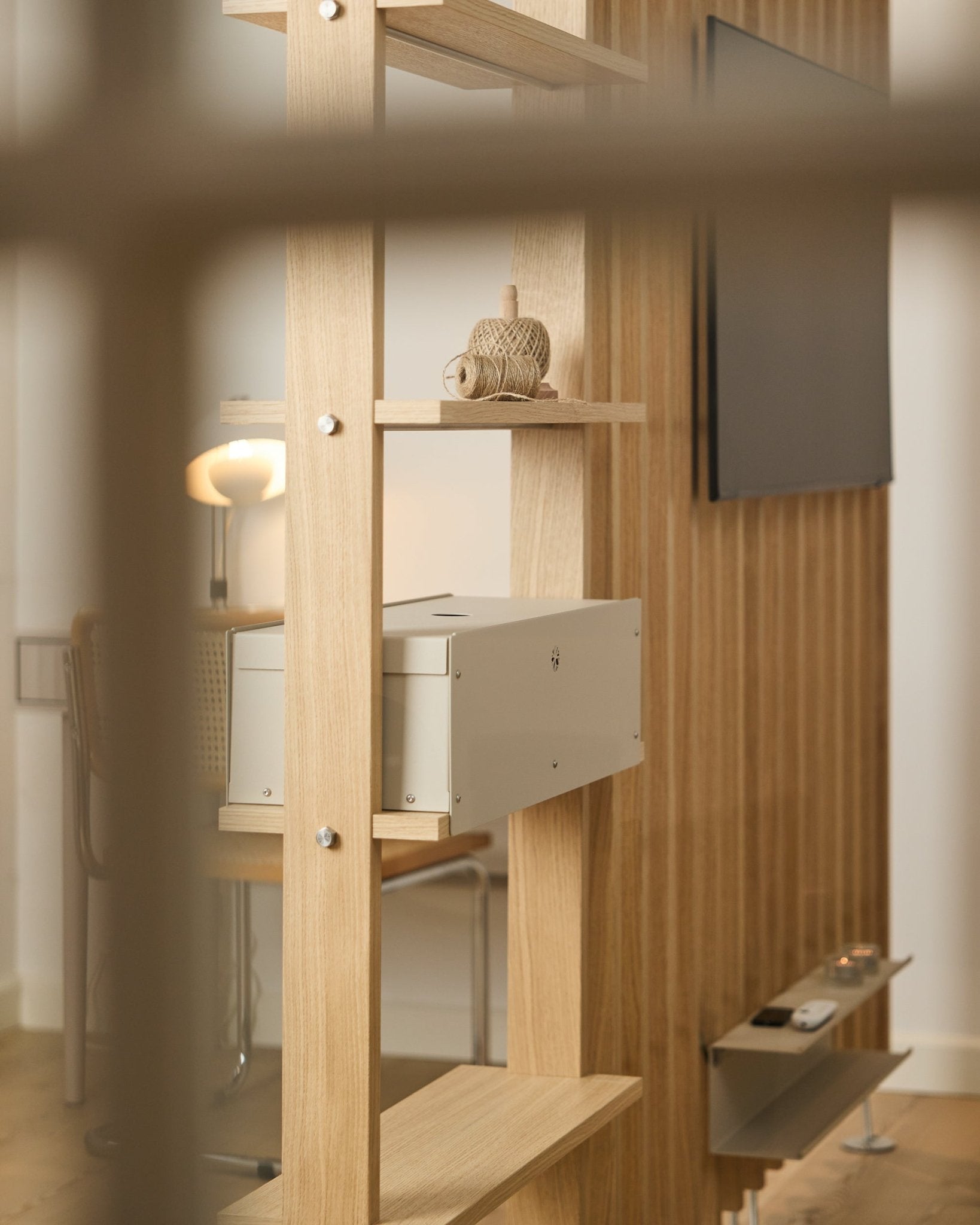 Una estancia acogedora con silla, lámpara y TV incluye la balda Nell | Metal Box / BM2 de WoodUpp, acabada en beige, con una decoración nórdica minimalista.