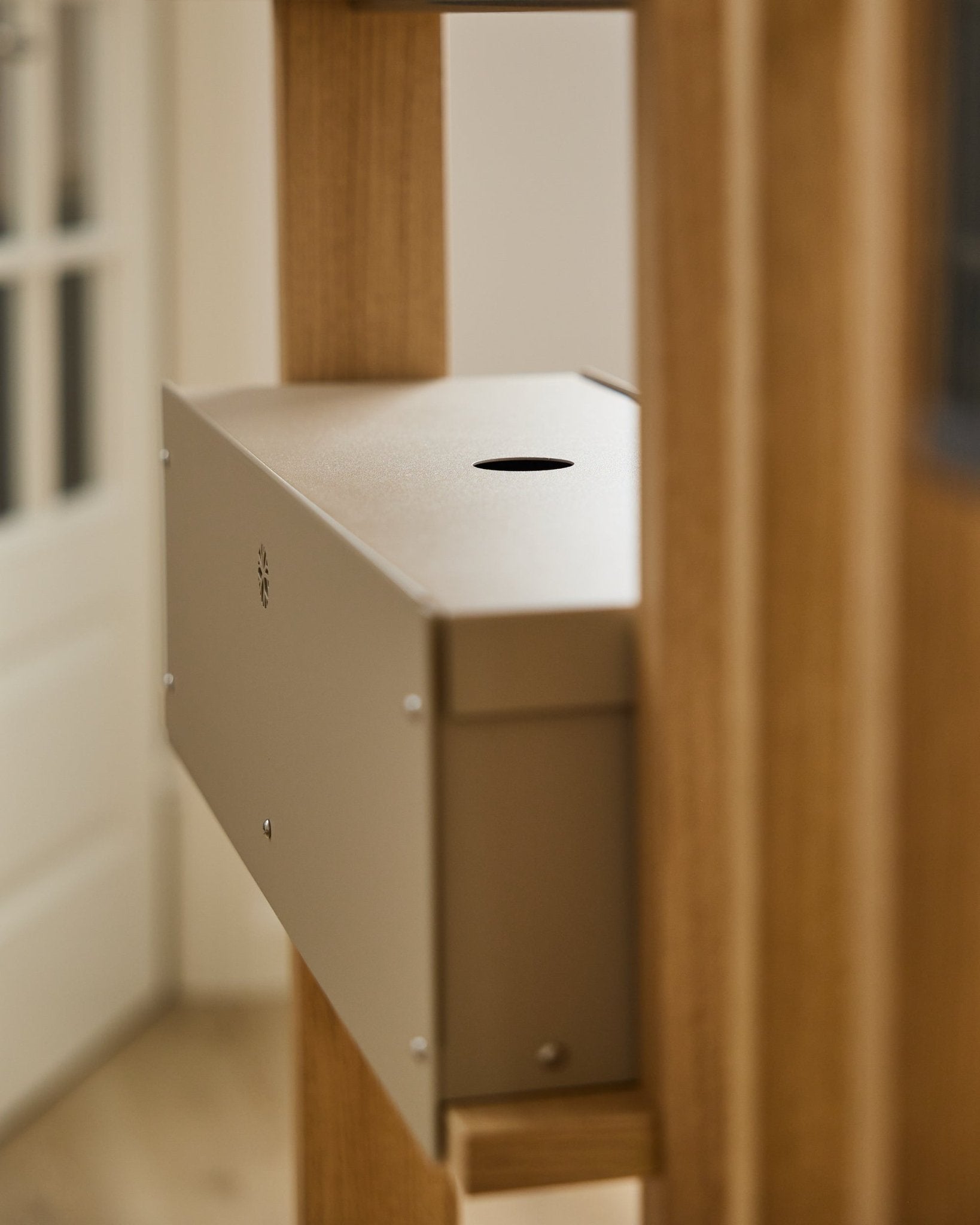 El Nell | Metal Box / BM2, Beige de WoodUpp es un accesorio de steel con recubrimiento en polvo de la colección CREATE, colocado entre paneles acústicos de madera junto a una puerta blanca.